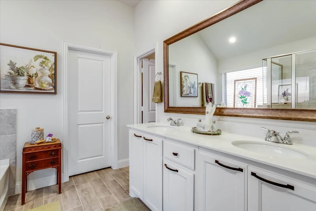 Double vanity featuring white cabinetry, solid-surface countertops, integrated dual sinks, and wood-finish flooring