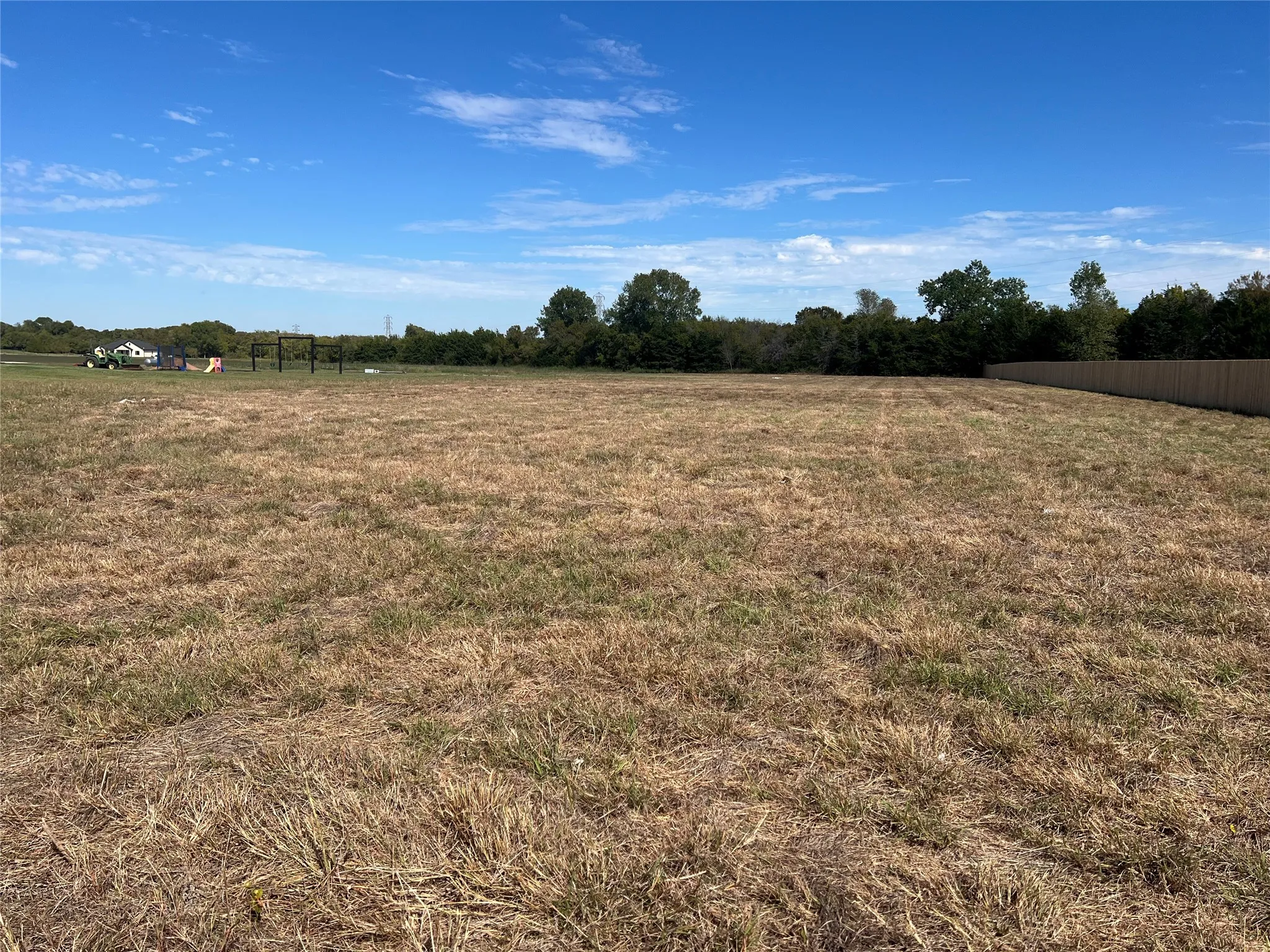 Expansive parcel of land featuring level terrain and perimeter wood fencing