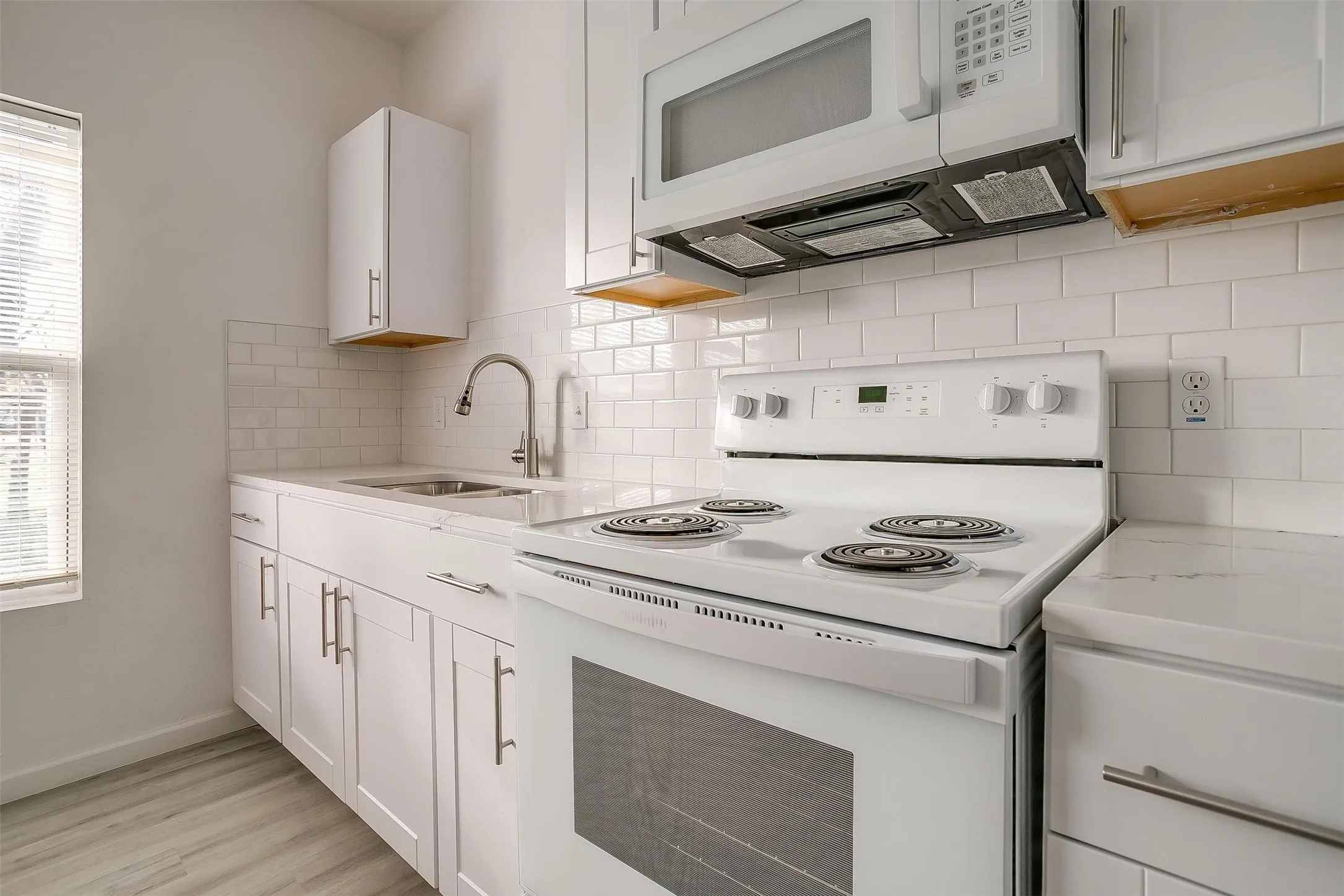 Kitchen featuring white cabinetry, subway tile backsplash, white electric range, over-the-range microwave, and wood-finish flooring