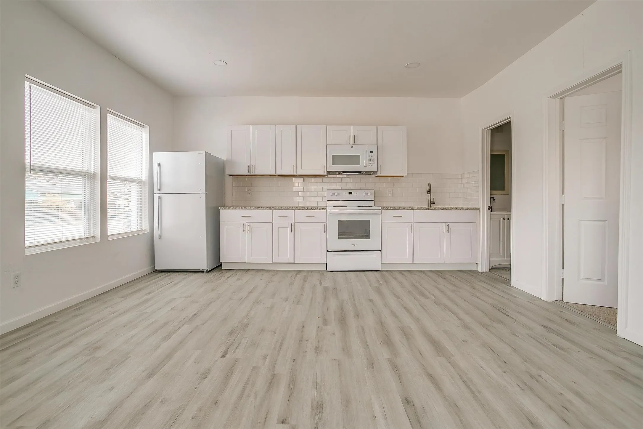 Kitchen featuring white cabinetry, subway tile backsplash, wood-finish flooring, built-in microwave, and recessed lighting