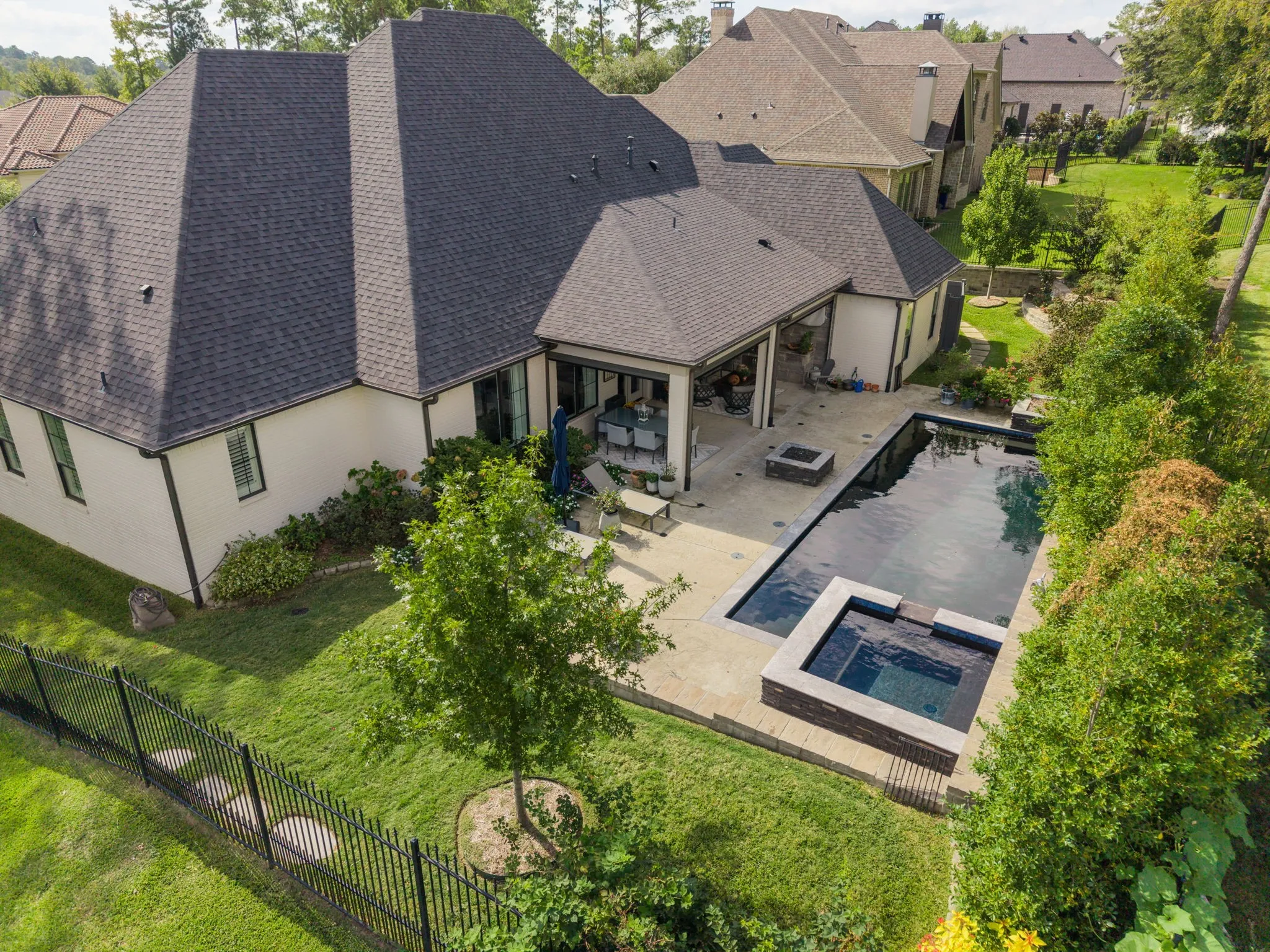 Backyard featuring a rectangular swimming pool, an integrated spa, a paved stone patio, and a fenced-in lawn area