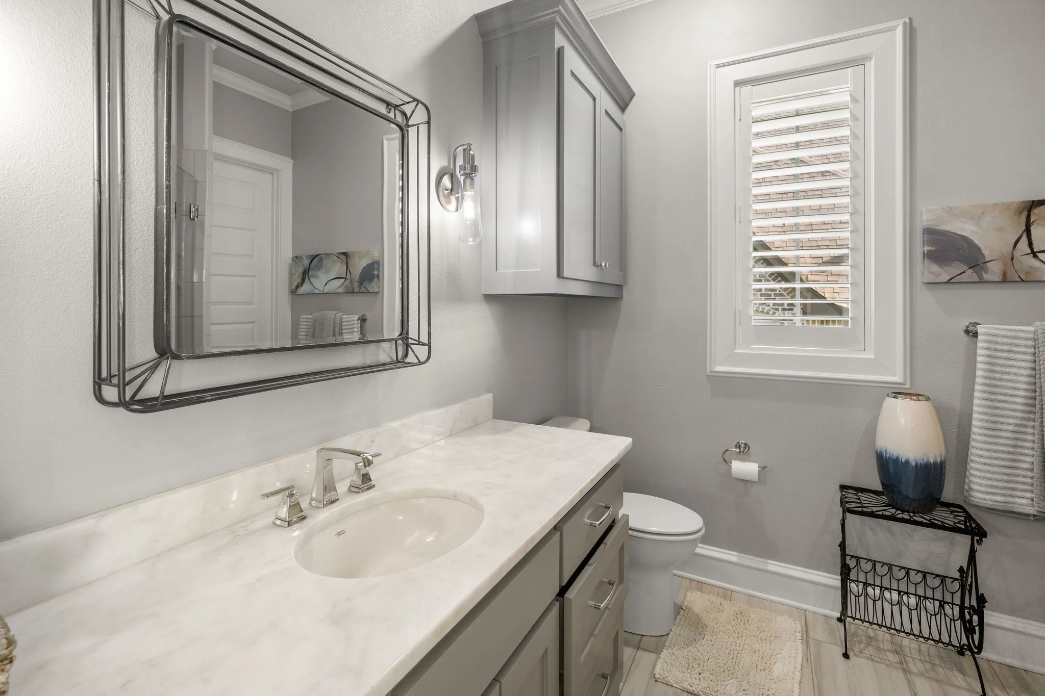 Vanity featuring a light-toned countertop, undermount sink, and wall-mounted metallic light fixture