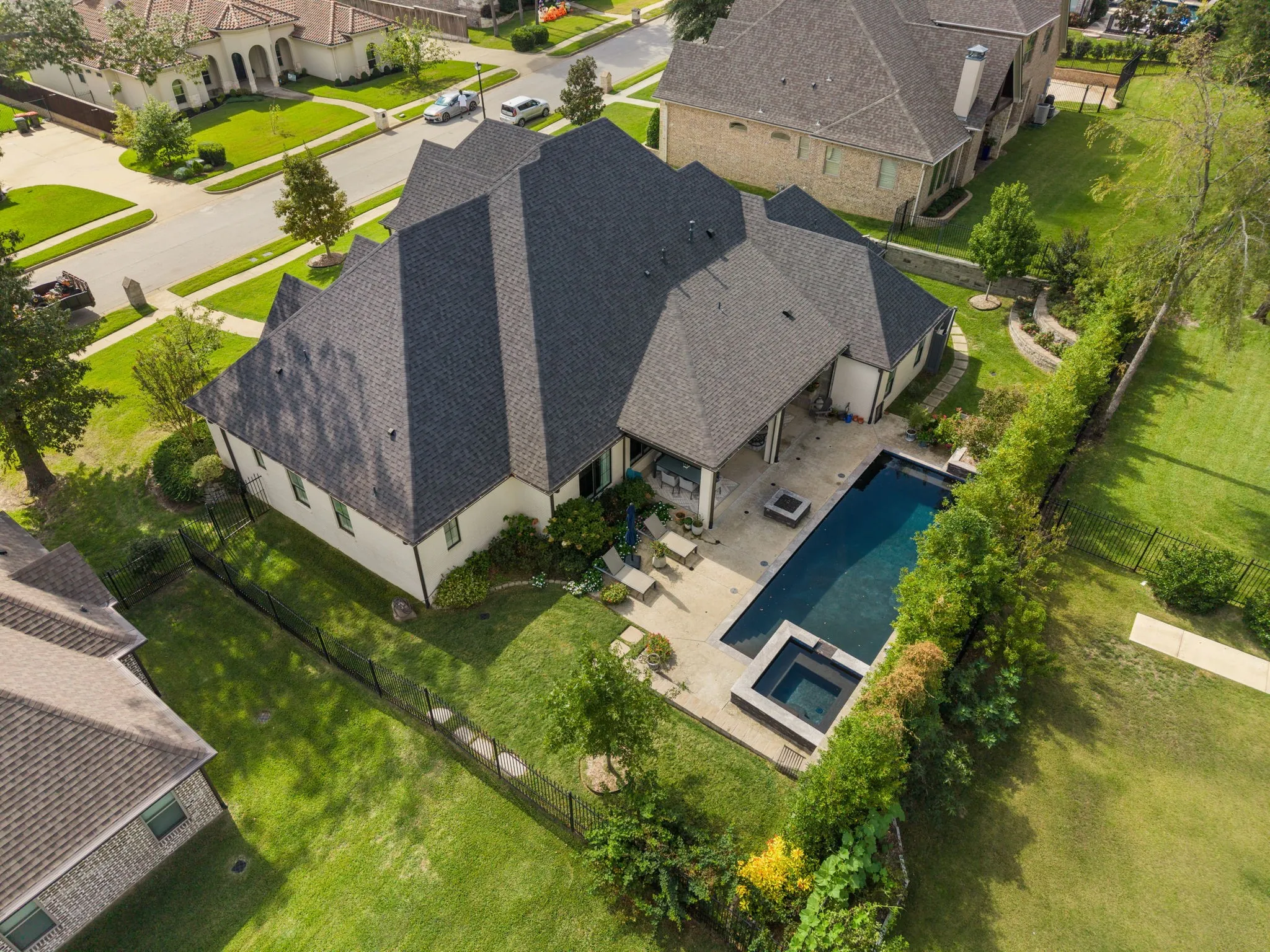 Multi-faceted roofline, covered rear patio, inground pool, integrated spa, and fenced backyard with manicured lawn