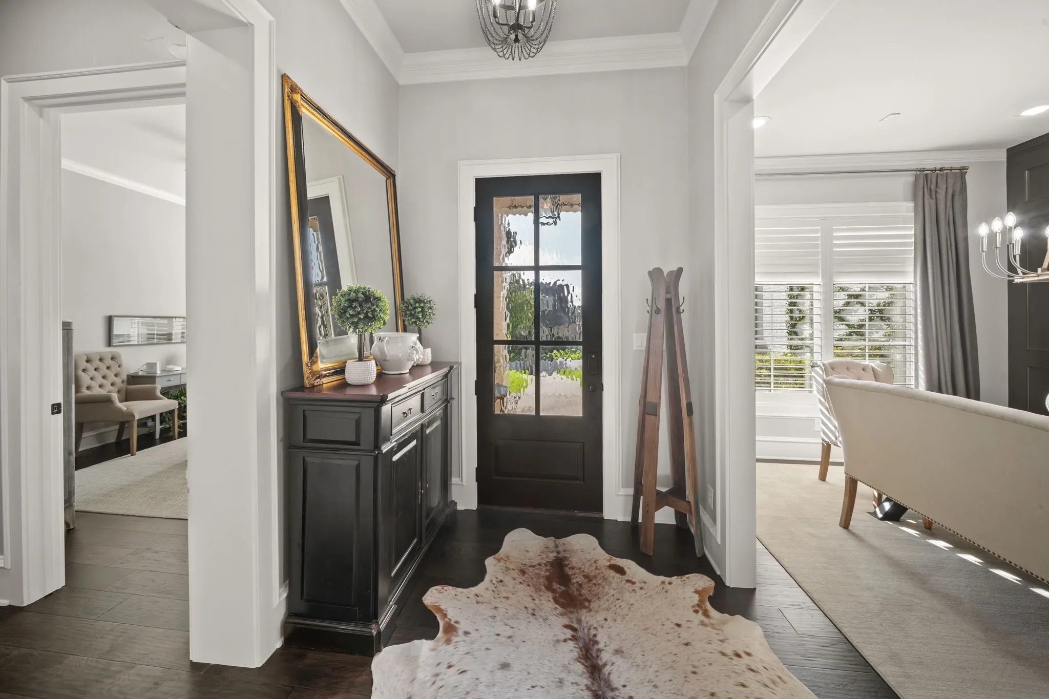 Entryway featuring dark-stained wood flooring, a multi-pane glass door, crown molding, and a decorative ceiling fixture
