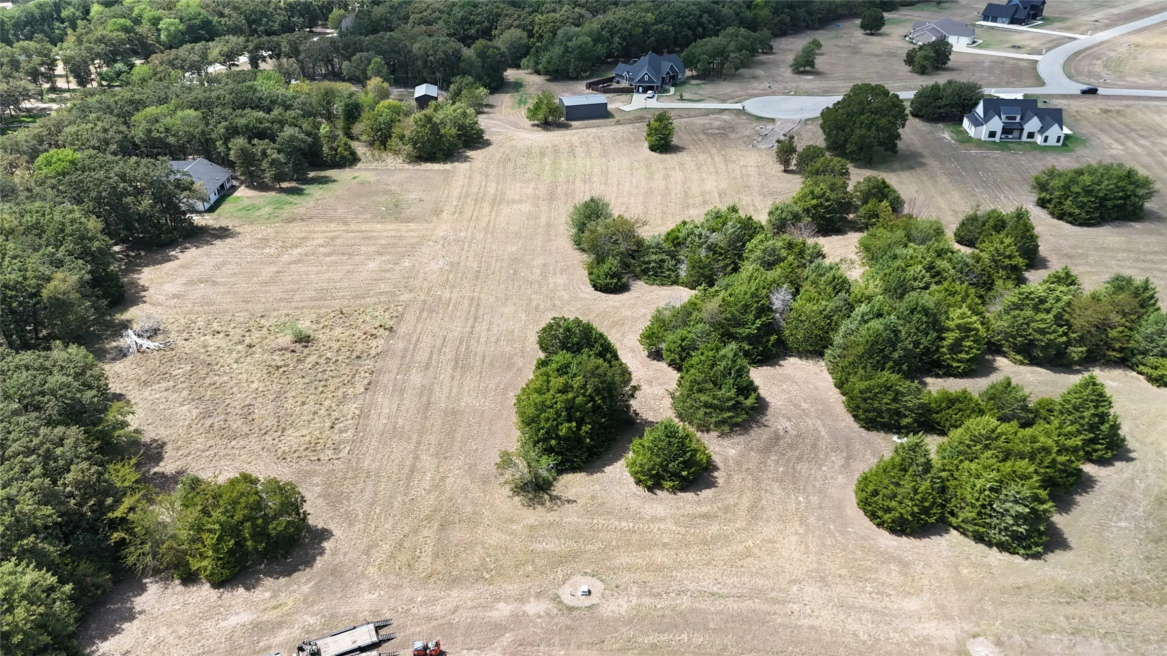 Expansive acreage featuring cleared land, clusters of mature trees, and natural vegetation