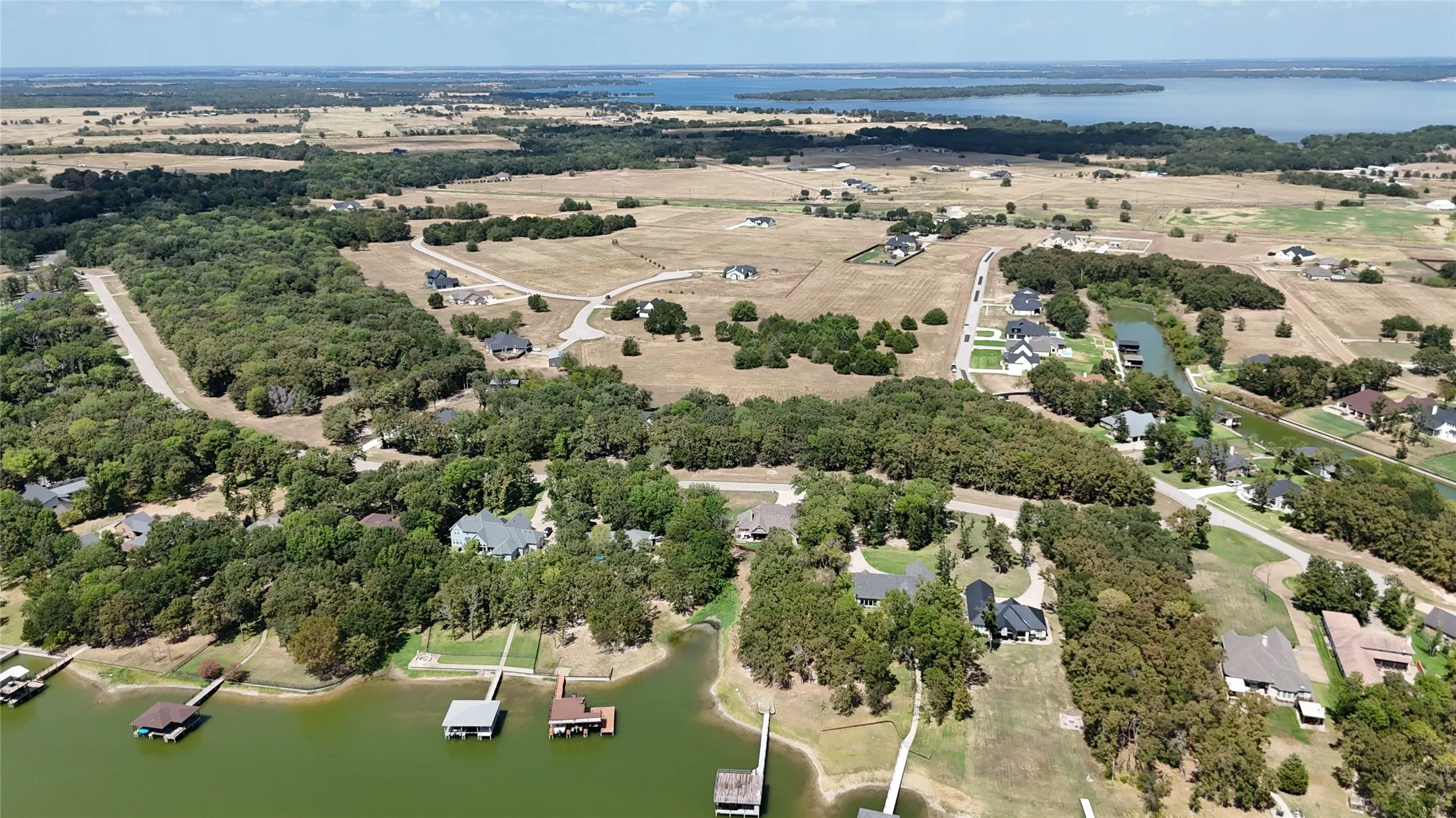 Aerial perspective of waterfront acreage featuring mature trees, private boat docks, and direct access to expansive open water