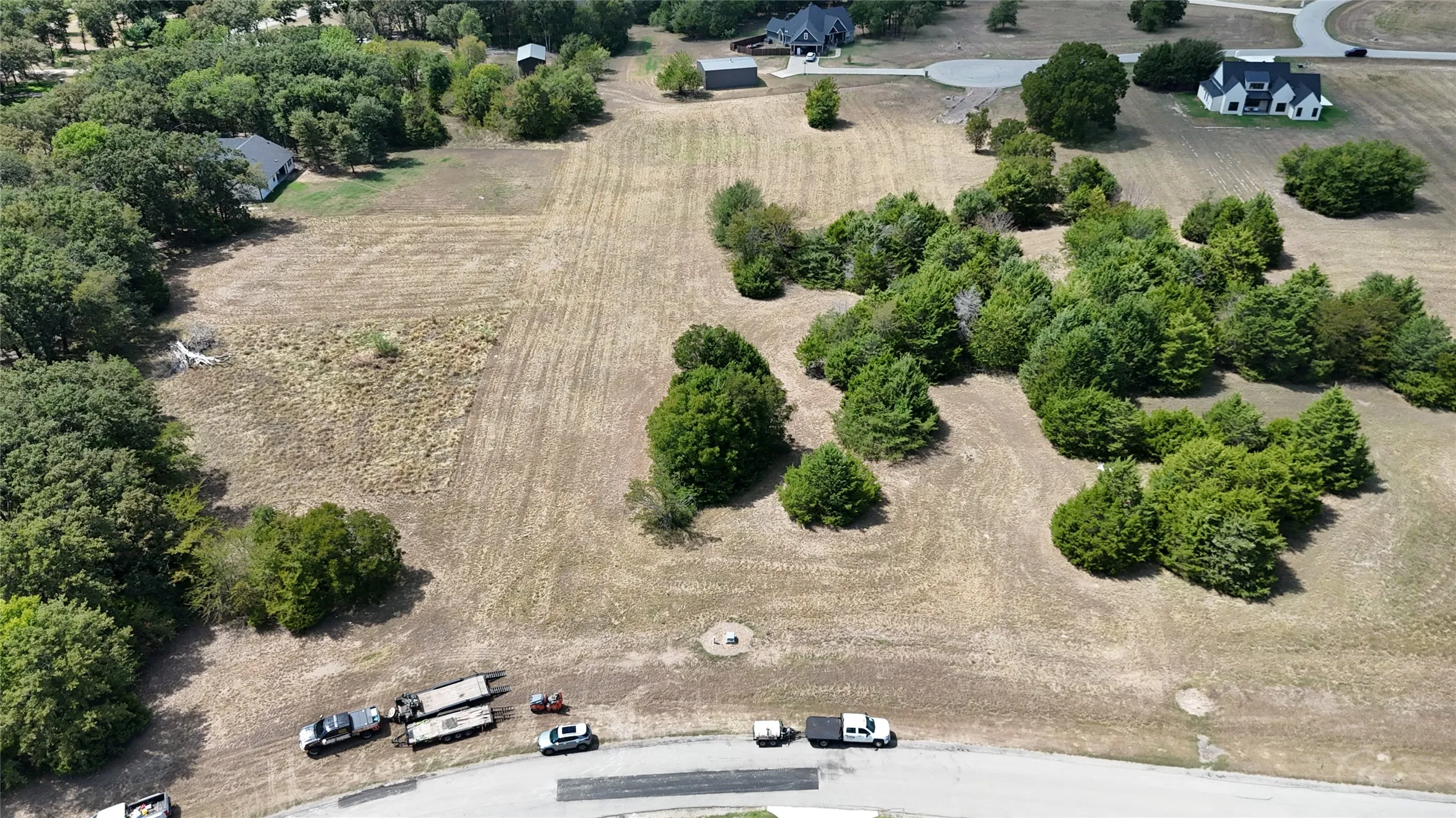 Expansive acreage featuring cleared level terrain and clusters of mature trees