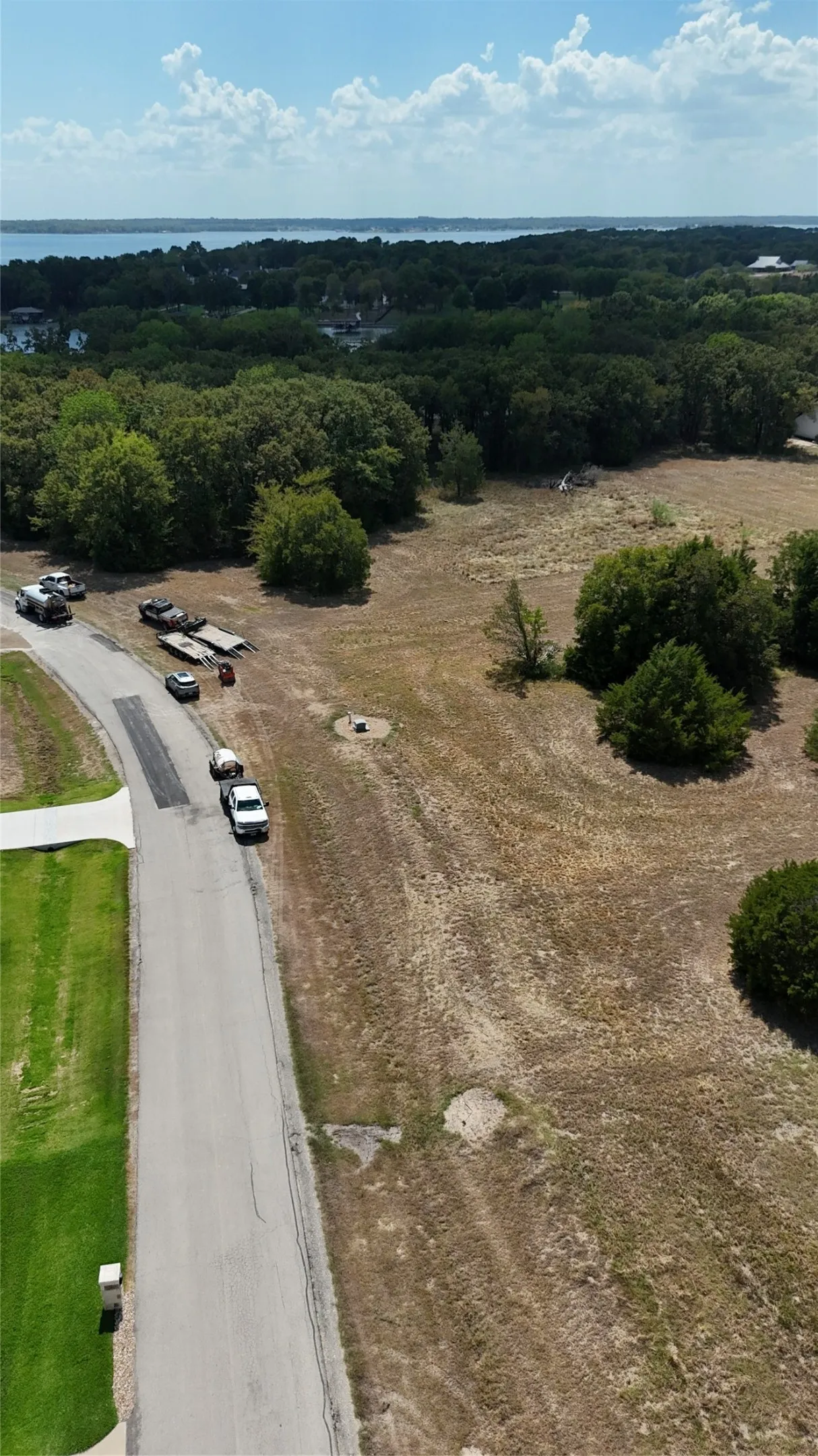 Expansive parcel of land featuring mature trees, open terrain, and water frontage