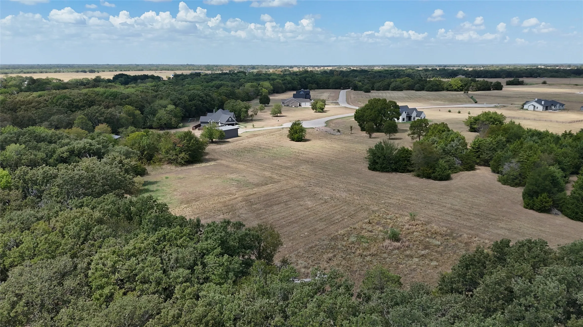 Expansive acreage featuring mature tree lines, open topography, and established rural road access