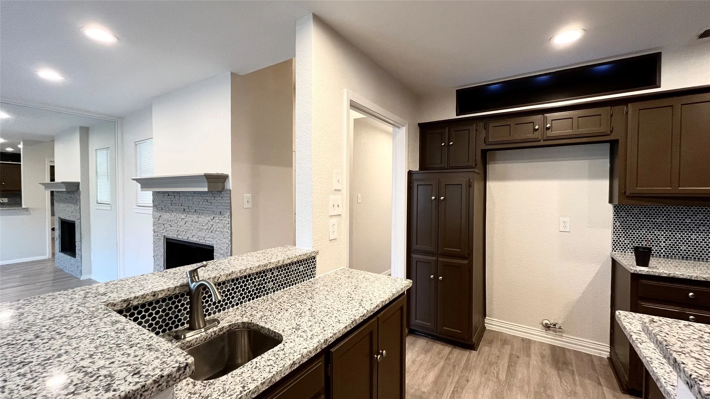 Kitchen featuring dark cabinetry, speckled stone-finish countertops, and an undermount stainless steel sink
