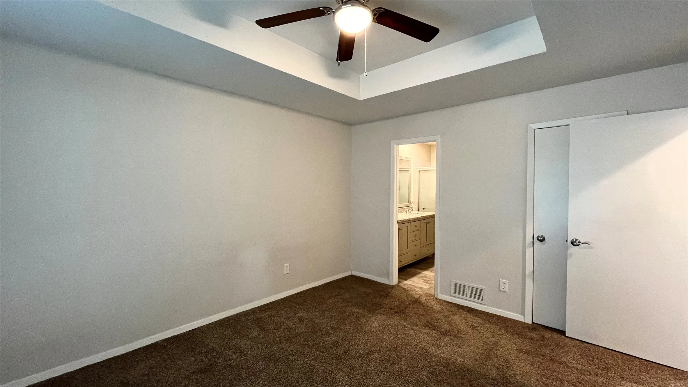 Bedroom featuring a tray ceiling, ceiling fan with light fixture, and neutral carpeting