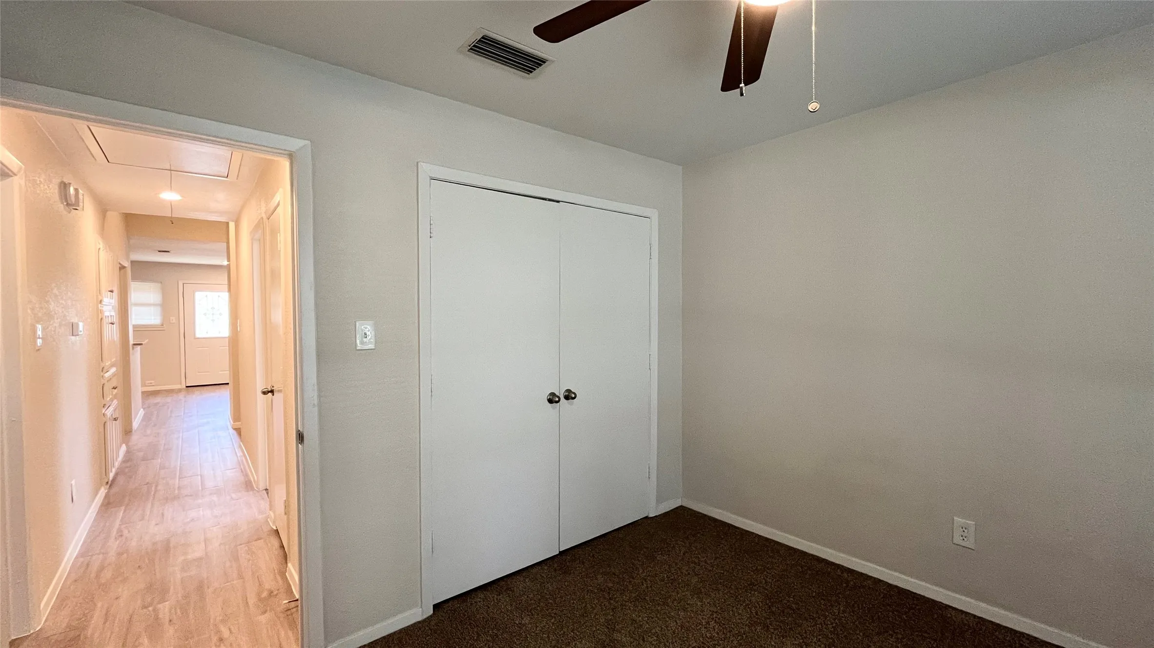 Room featuring brown carpeting, a double-door closet with spherical knobs, and a ceiling fan with integrated lighting