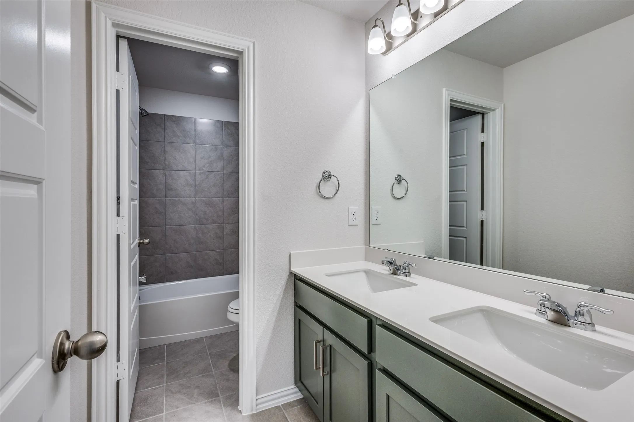 Full bath featuring toilet, tile patterned flooring, double vanity, and a sink