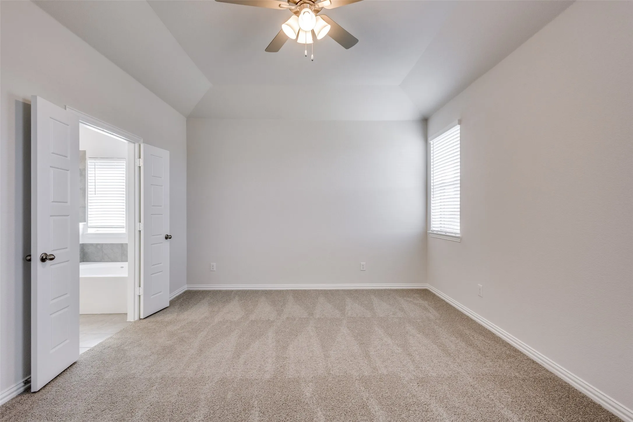 Empty room with light colored carpet, baseboards, and a ceiling fan