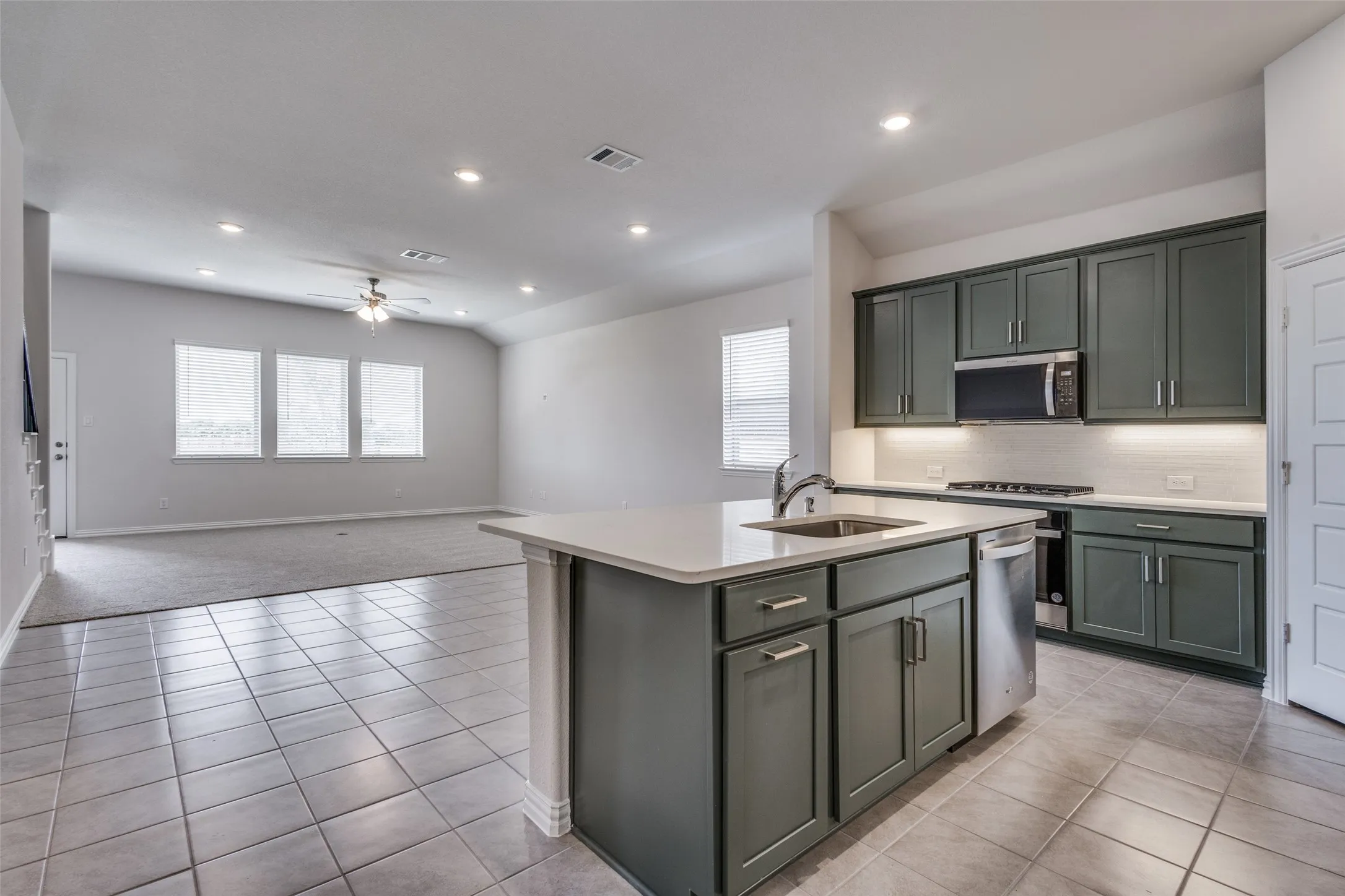 Kitchen with stainless steel appliances, ceiling fan, visible vents, a sink, and light countertops