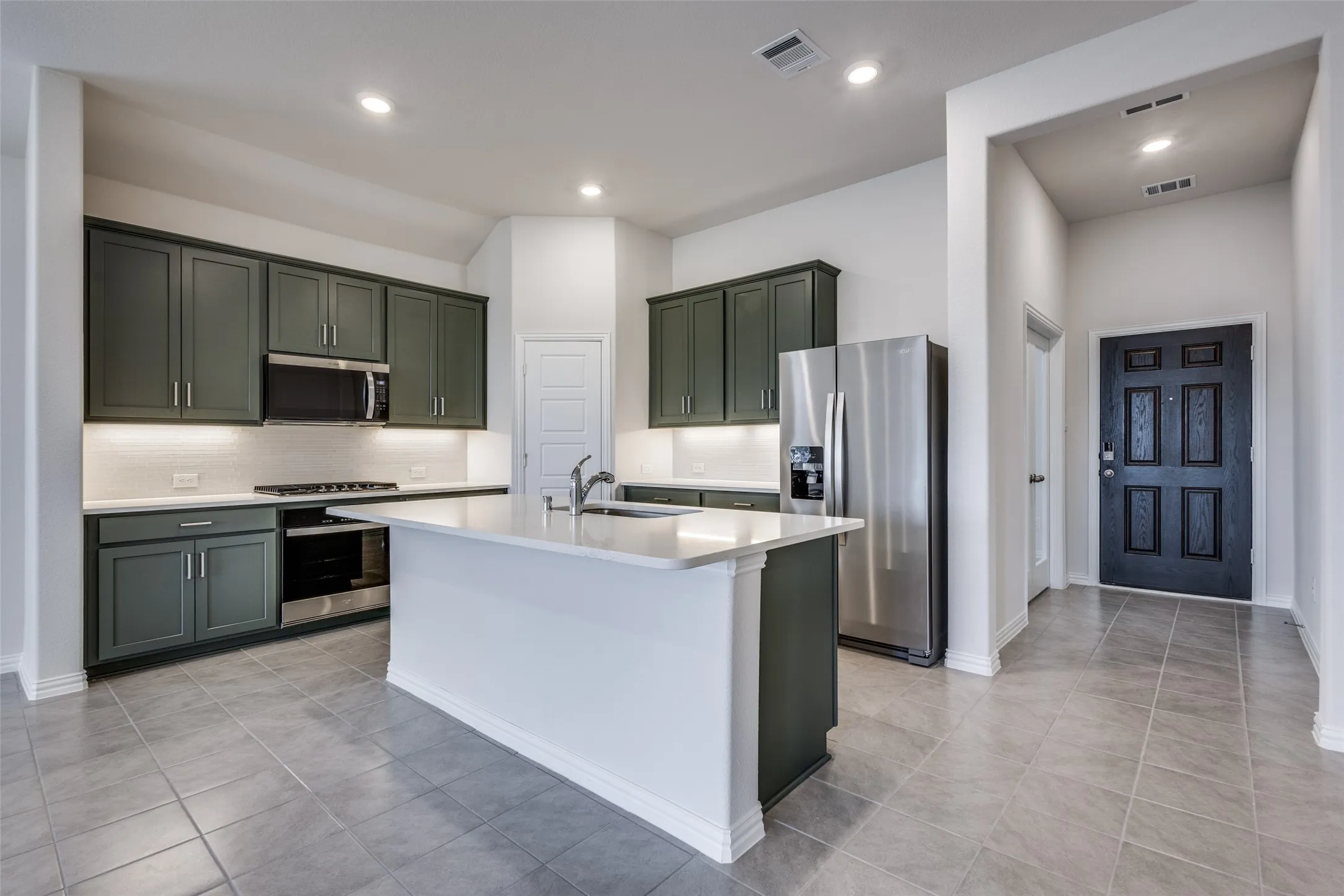 Kitchen featuring a sink, visible vents, light countertops, appliances with stainless steel finishes, and decorative backsplash