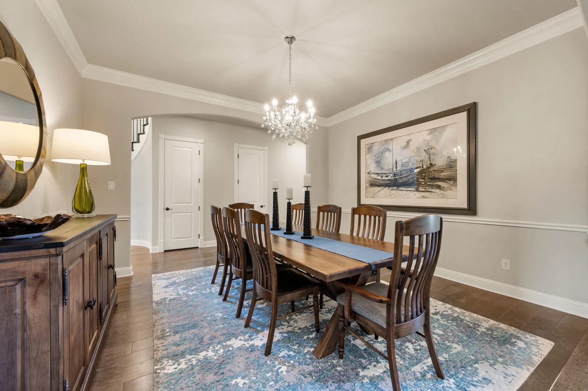 Formal dining area featuring wood-finish flooring, crown molding, chair rail trim, and a multi-tiered crystal chandelier