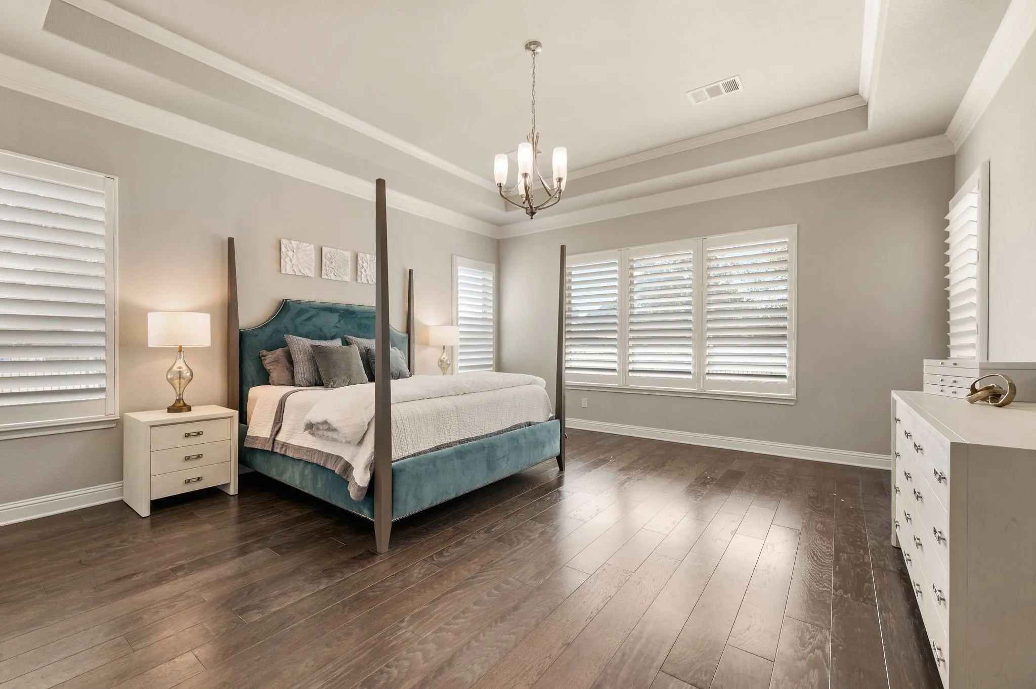 Tray ceiling with crown molding, wood-finish flooring, and window shutters