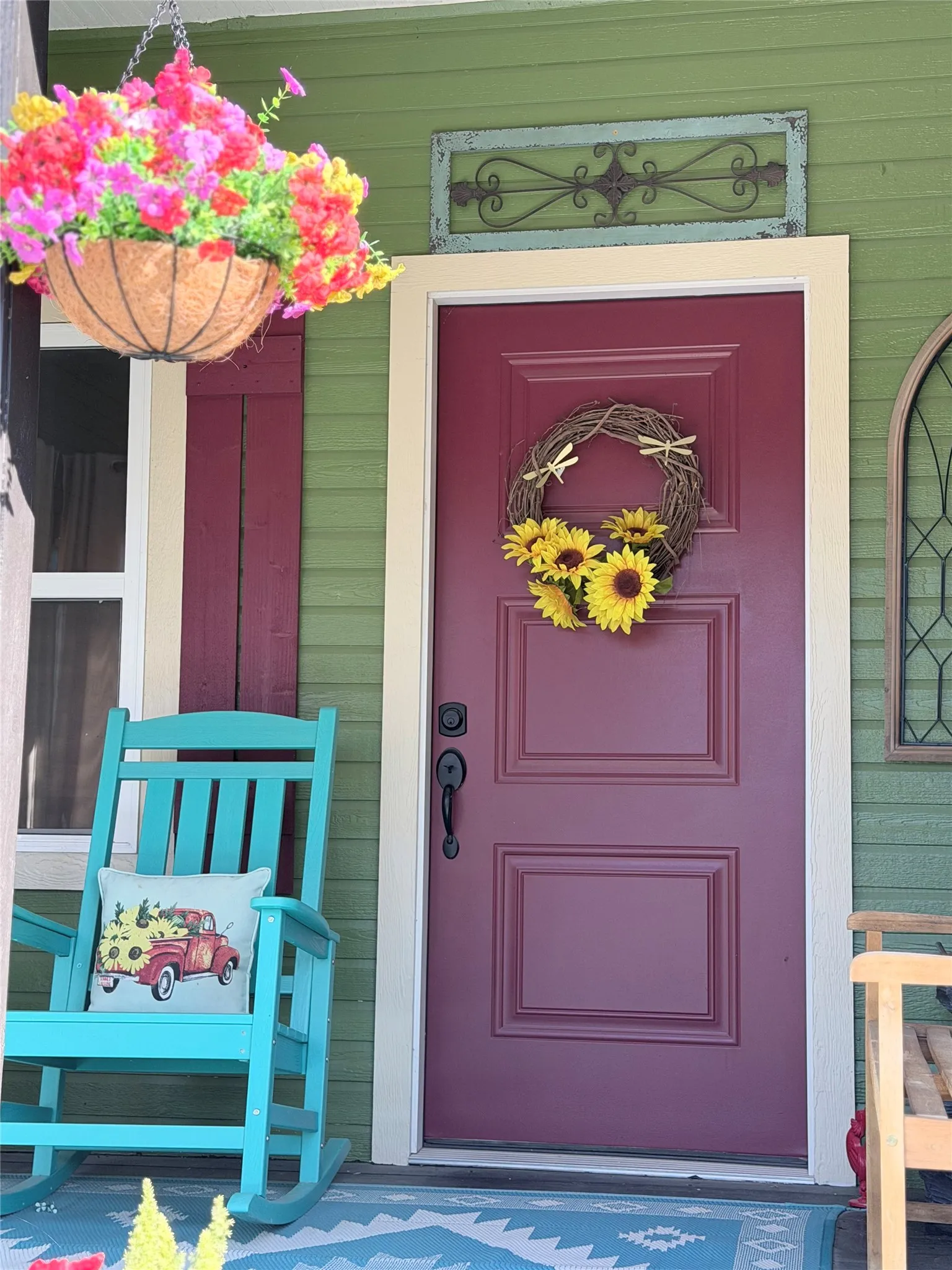 Covered entryway featuring horizontal lap siding, a paneled solid door with matte black hardware, and decorative metal wall accent