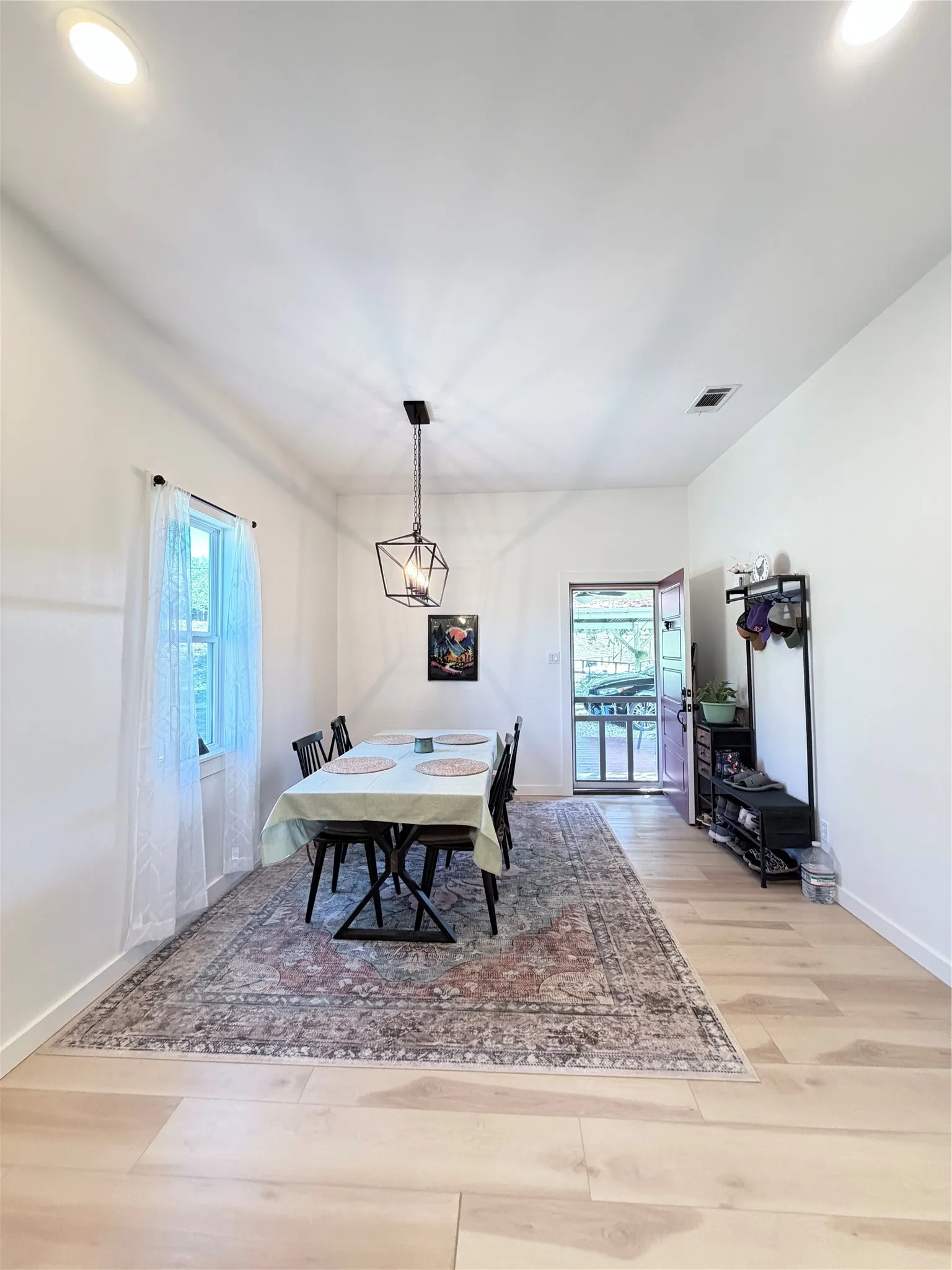 Light-filled room featuring wood-finish flooring, recessed ceiling lighting, and a geometric metal pendant light fixture