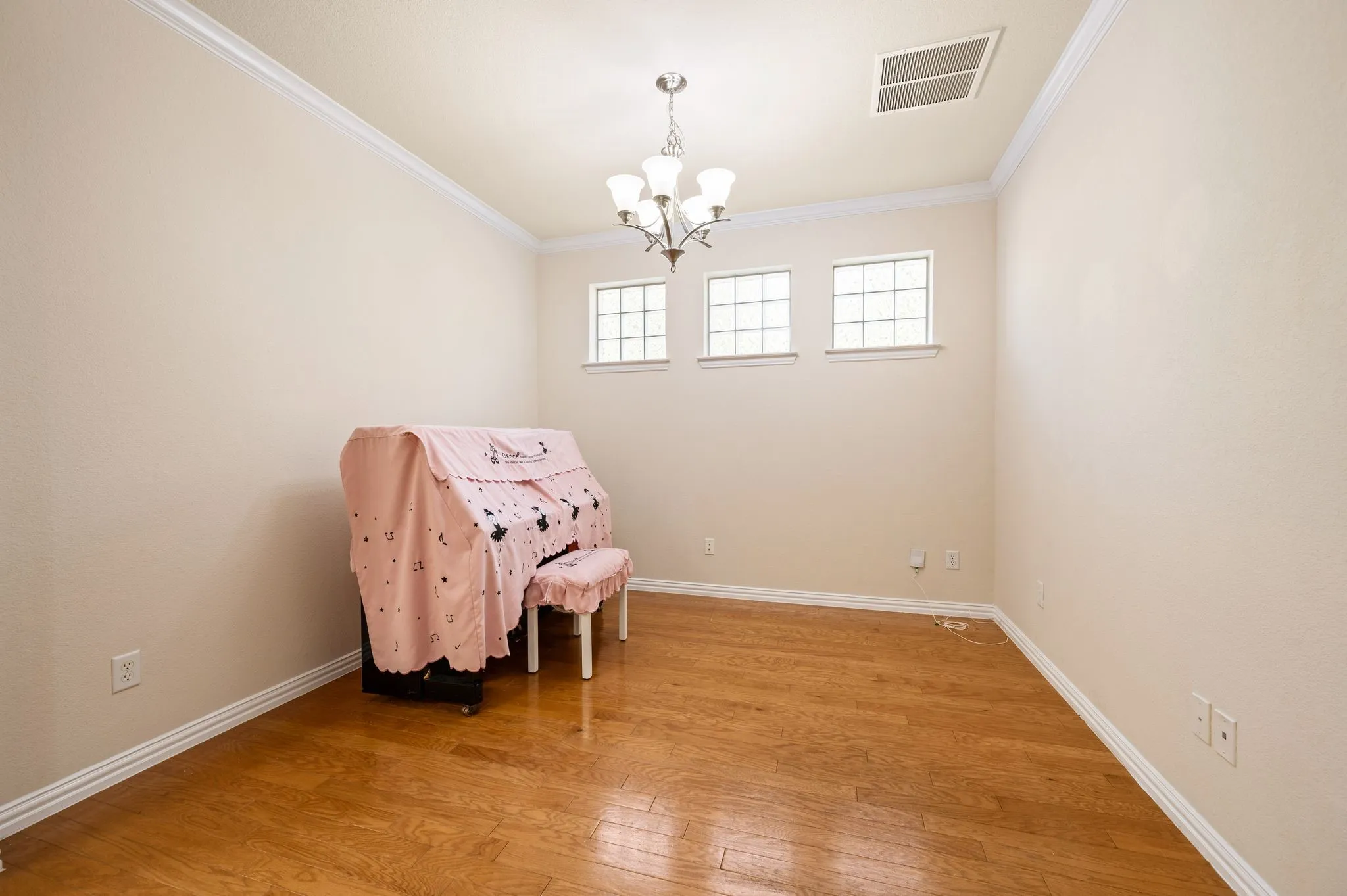 Interior space featuring wood-finish flooring, crown molding, a multi-light chandelier, and three transom-style windows