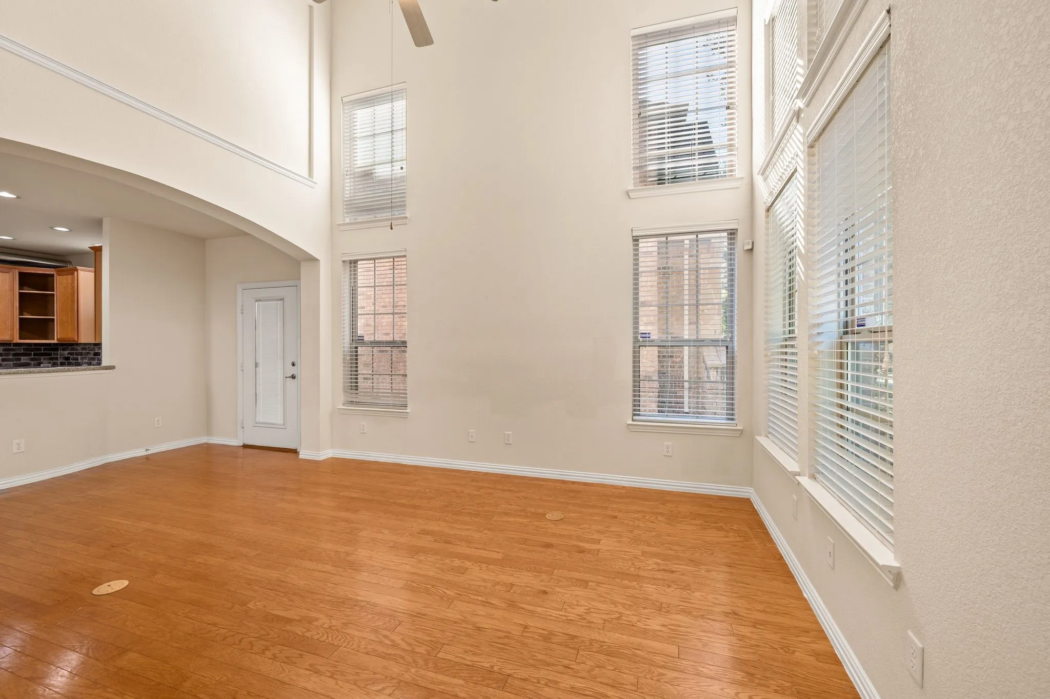 High-ceiling room featuring wood-finish flooring, multi-level windows, and crown molding