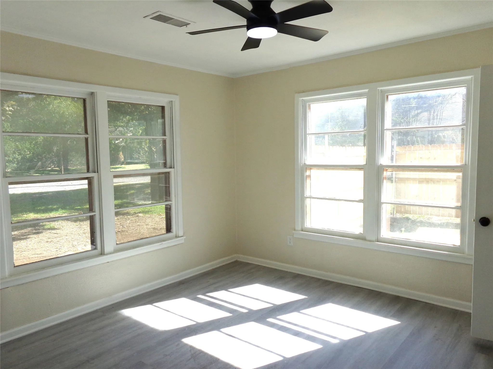 Neutral wall tones, wood-finish flooring, and multiple large windows with white trim