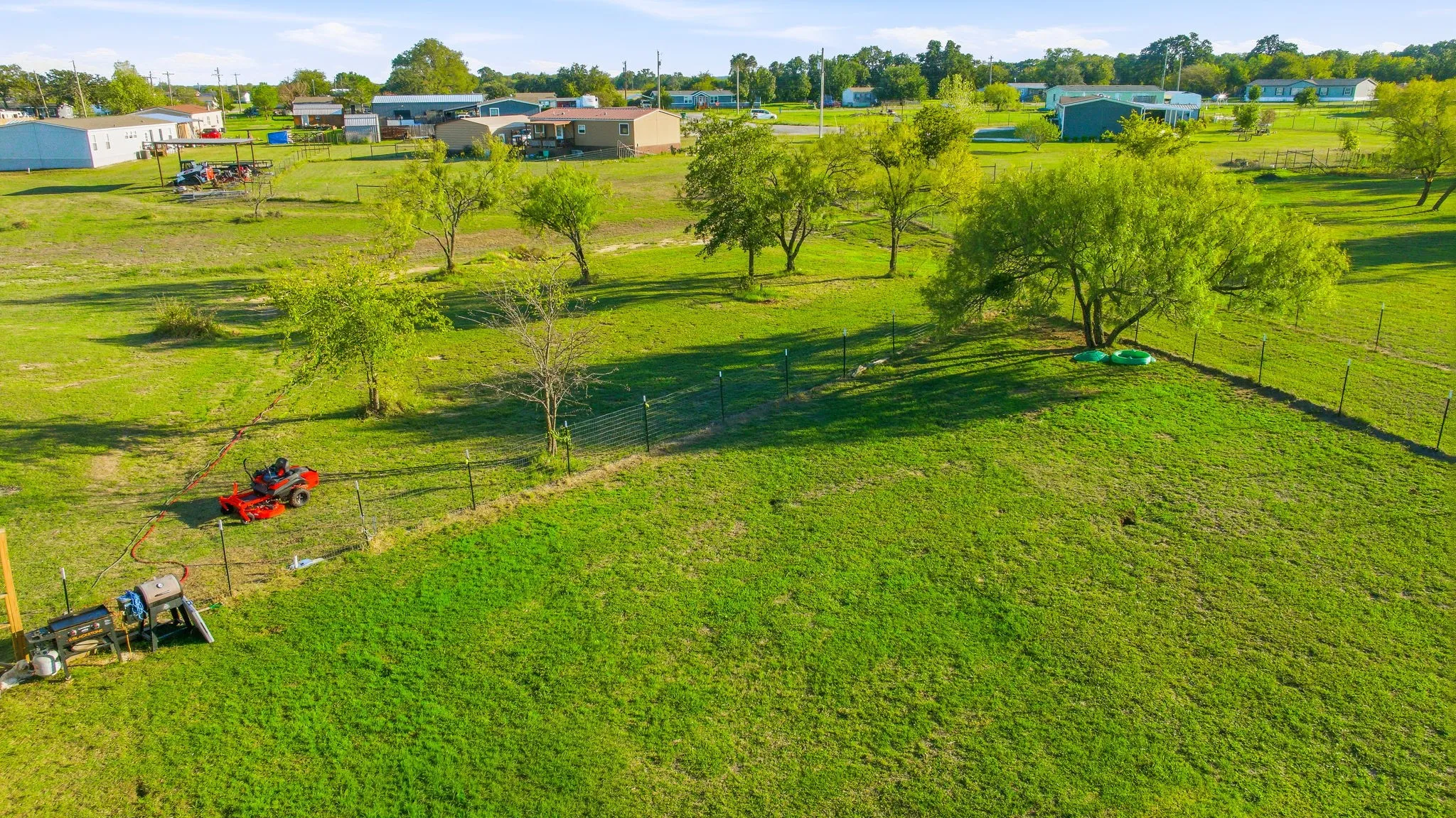 Expansive acreage featuring mature trees, perimeter wire fencing, and open grass fields