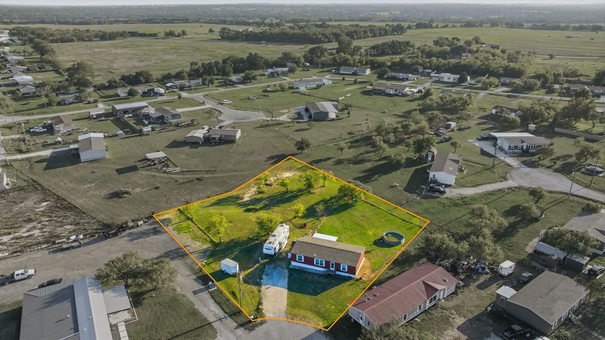 Expansive lot featuring mature trees, a designated gravel driveway, and perimeter fencing