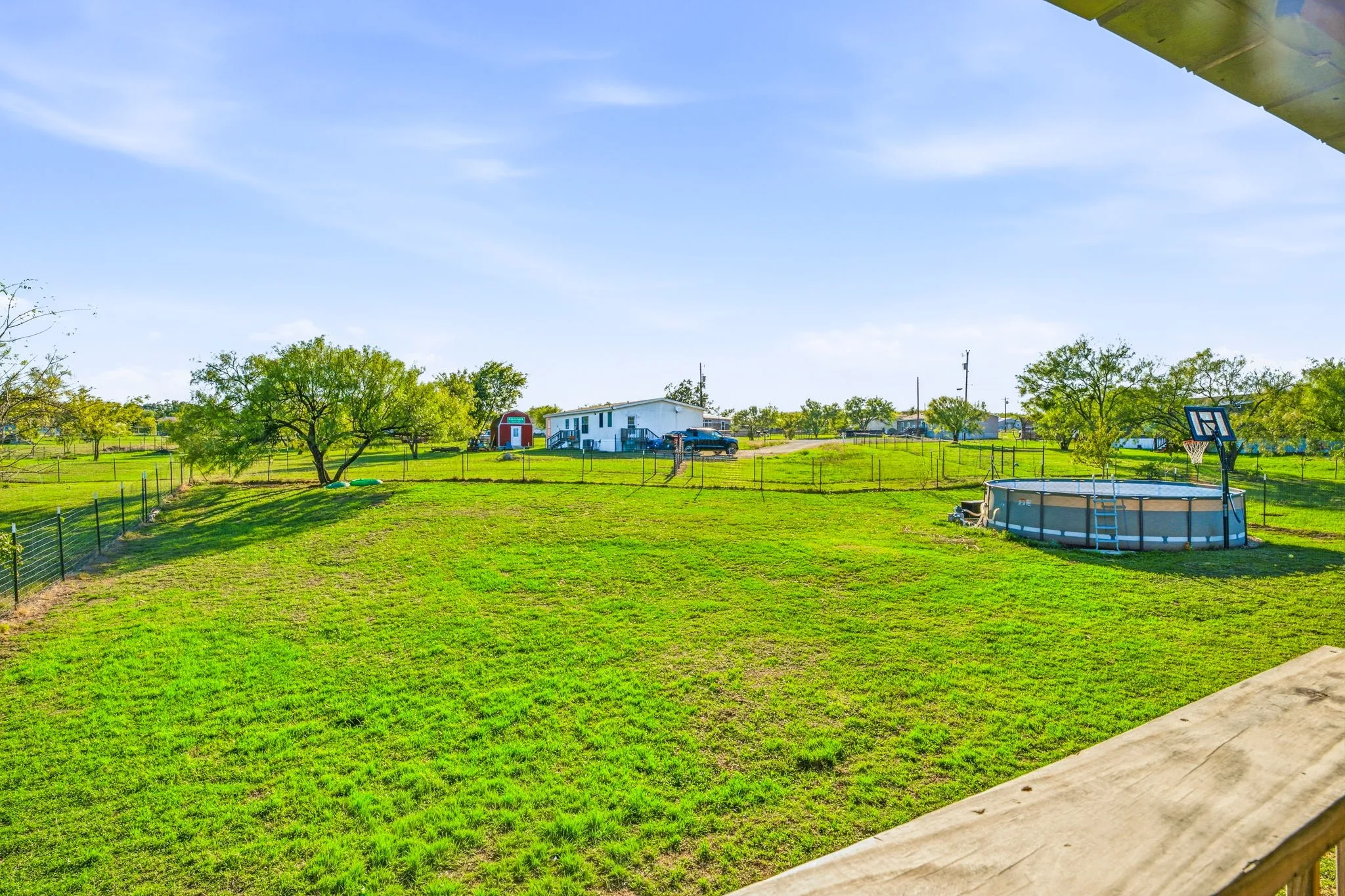Expansive grounds featuring a fenced perimeter, mature trees, and a detached storage shed