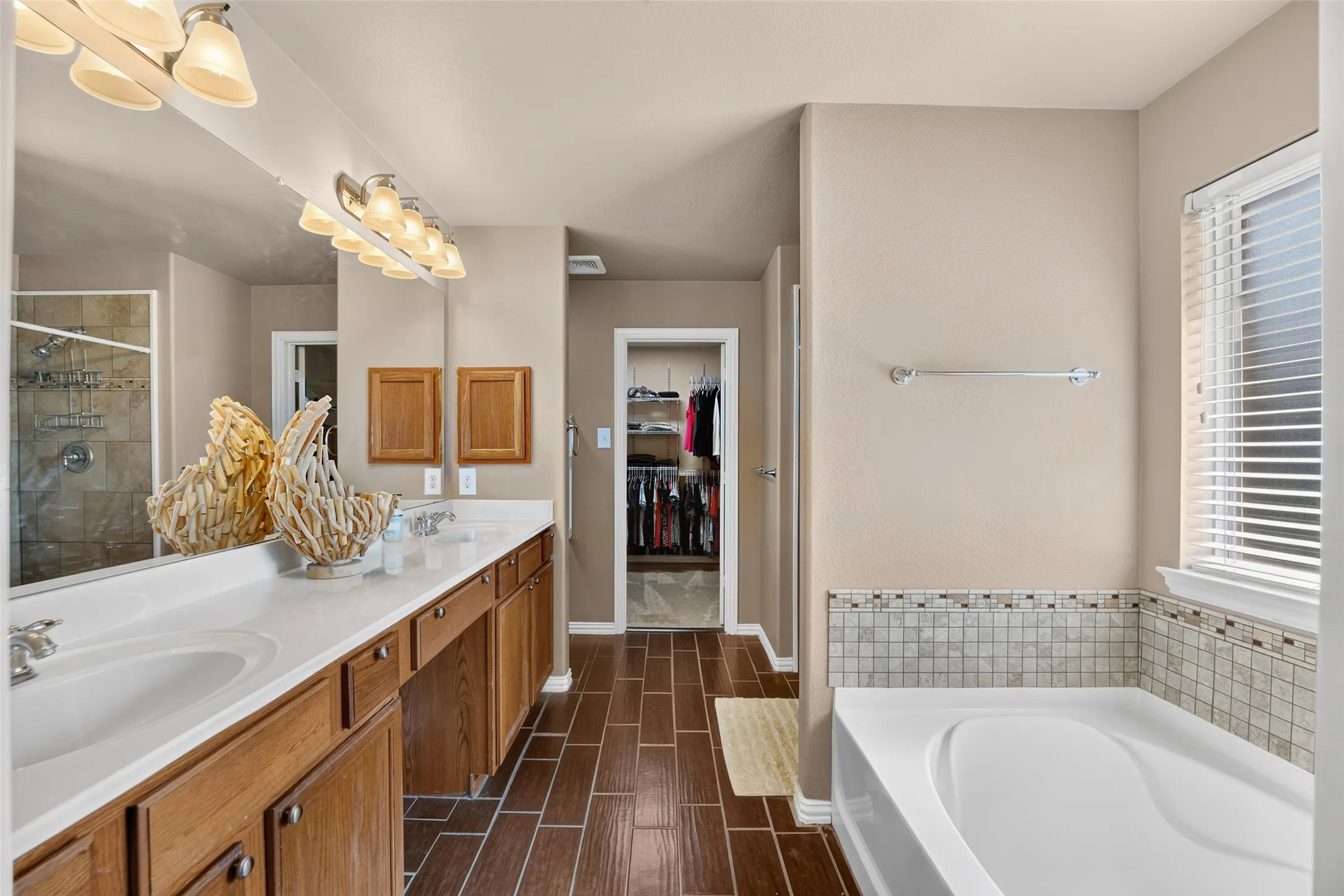 Well-appointed primary bath featuring dual vanities, a relaxing soaking tub, separate walk-in shower, and direct access to the spacious walk-in closet.