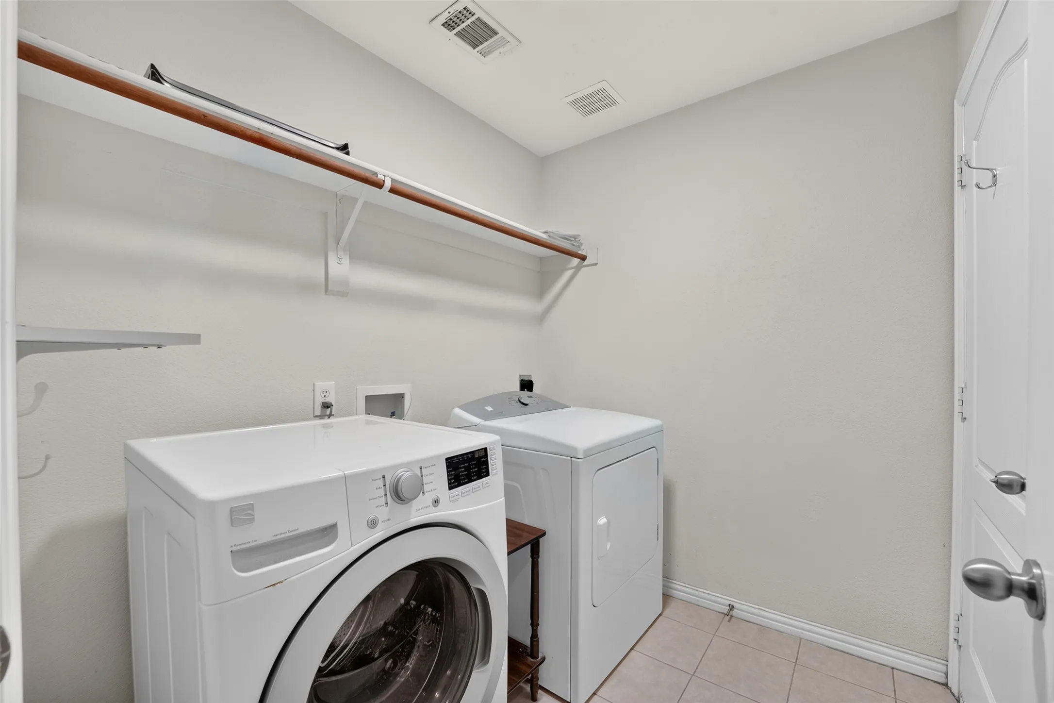 Laundry room featuring tile flooring, neutral wall paint, and overhead shelf storage.  WASHER & DRYER CONVEY!