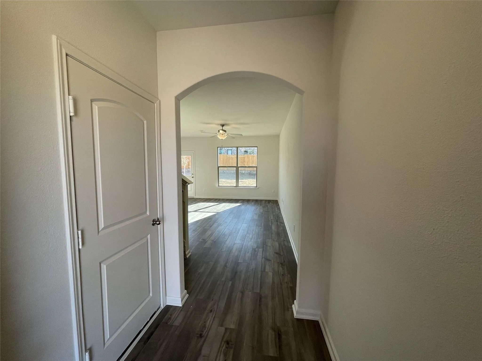 Interior entryway featuring an arched passage, wood-finish flooring, and a two-panel interior door with brushed nickel hardware