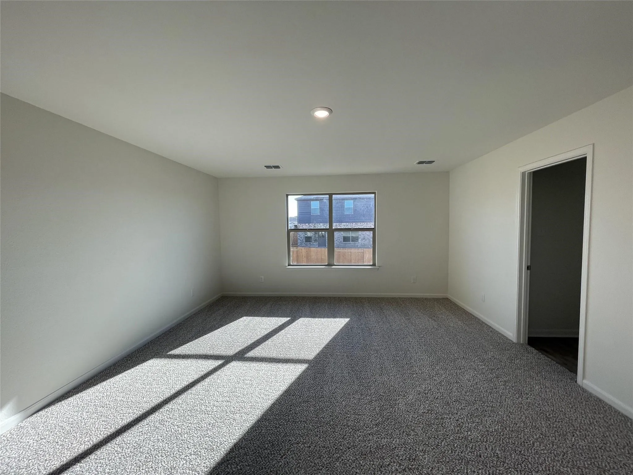 Neutral-toned interior space featuring neutral carpeting, a central recessed light fixture, and a single-pane window with a sill