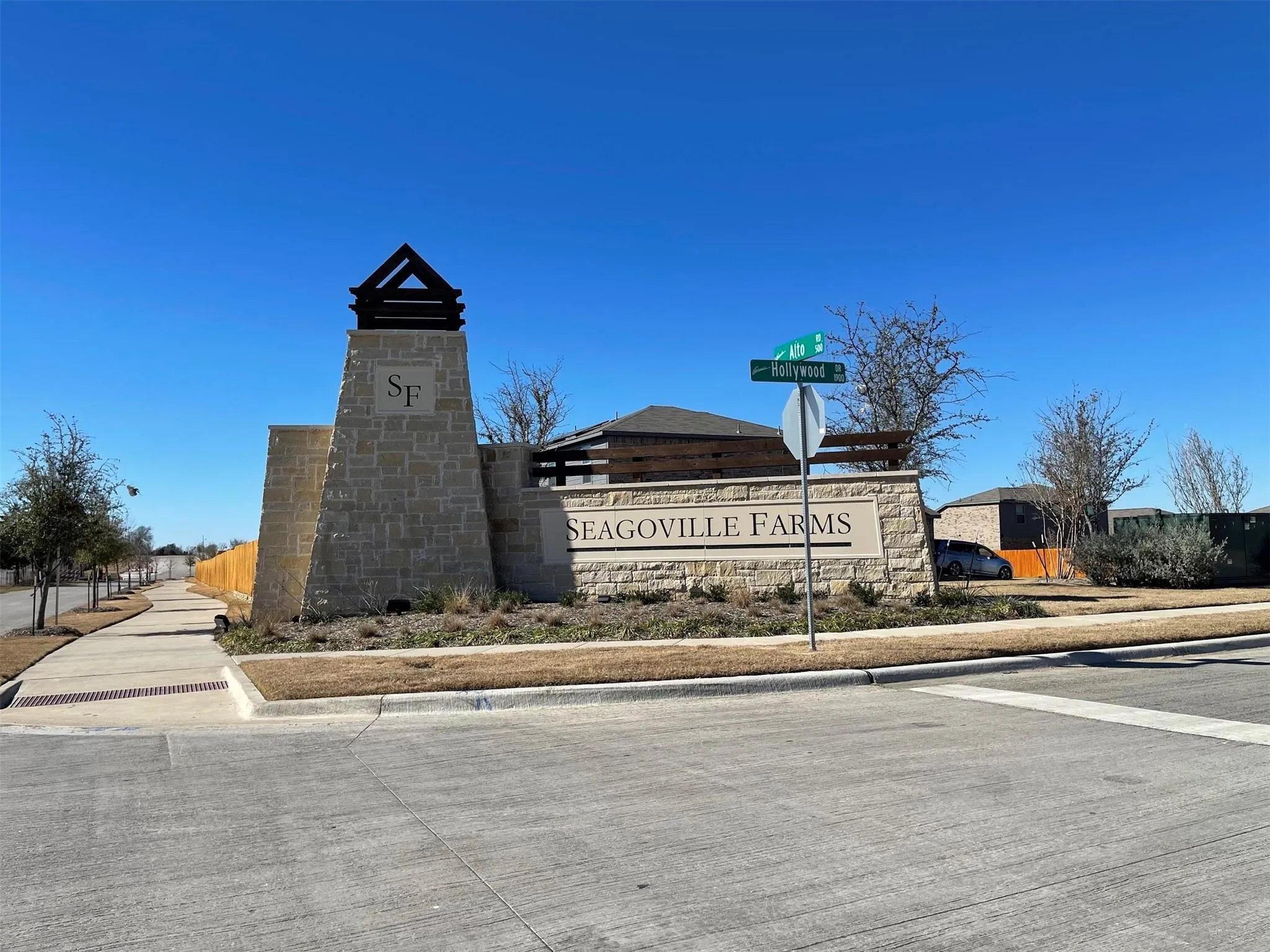 Stone monument entrance featuring a tapered architectural tower, decorative timber accents, and integrated signage