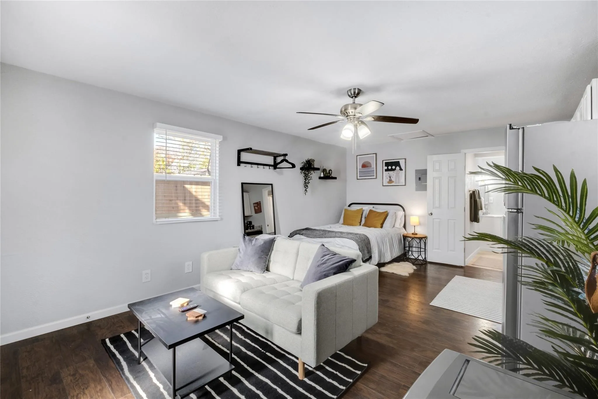 Wood-finish flooring, multi-blade ceiling fan with integrated lighting, and white six-panel interior door
