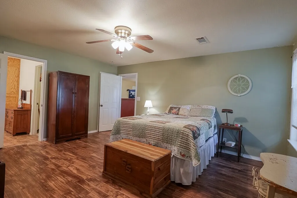 Room featuring wood-finish flooring, a multi-blade ceiling fan with integrated lighting, and painted walls