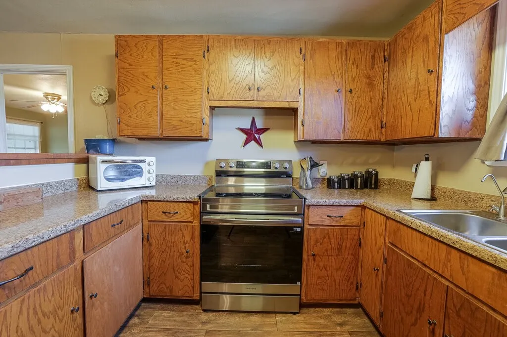 Kitchen featuring wood cabinetry, solid-surface countertops, wood-finish flooring, and a stainless steel freestanding range
