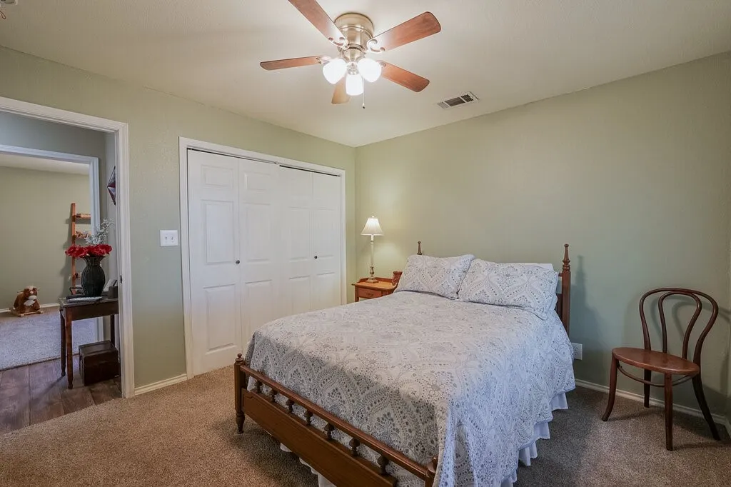 Bedroom interior featuring neutral wall paint, wall-to-wall carpeting, and a multi-light ceiling fan