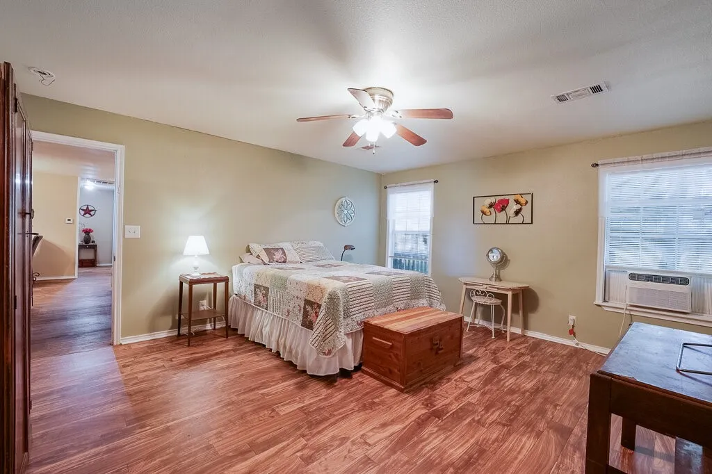 Bedroom featuring wood-finish flooring, a ceiling fan with integrated lighting, and multiple windows