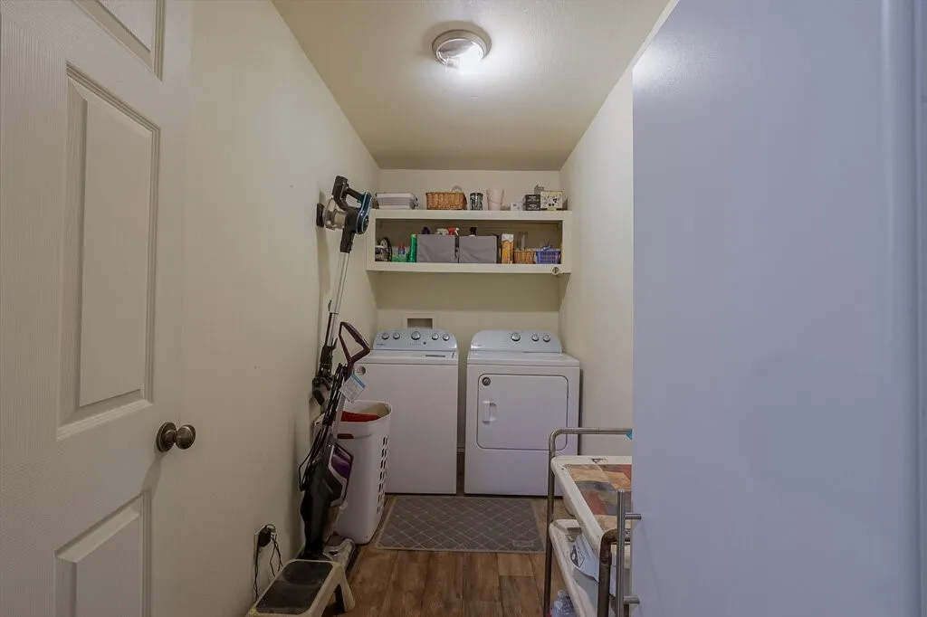 Laundry area featuring wood-finish flooring, ceiling-mounted lighting, and built-in upper shelving