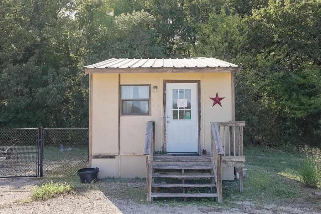 Detached structure featuring a metal roof, single-pane window, and exterior wood-stair entry with railing