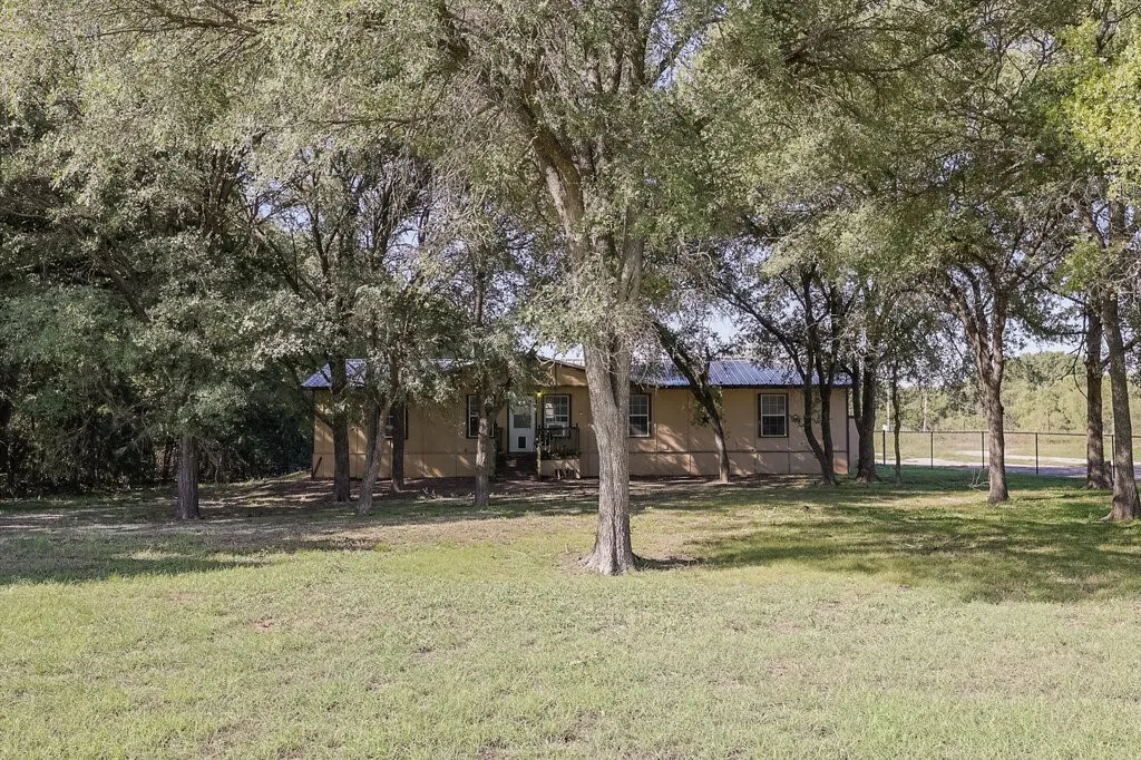 Single-story residence featuring a metal roof, exterior siding, and a fenced perimeter situated on a lot with mature trees