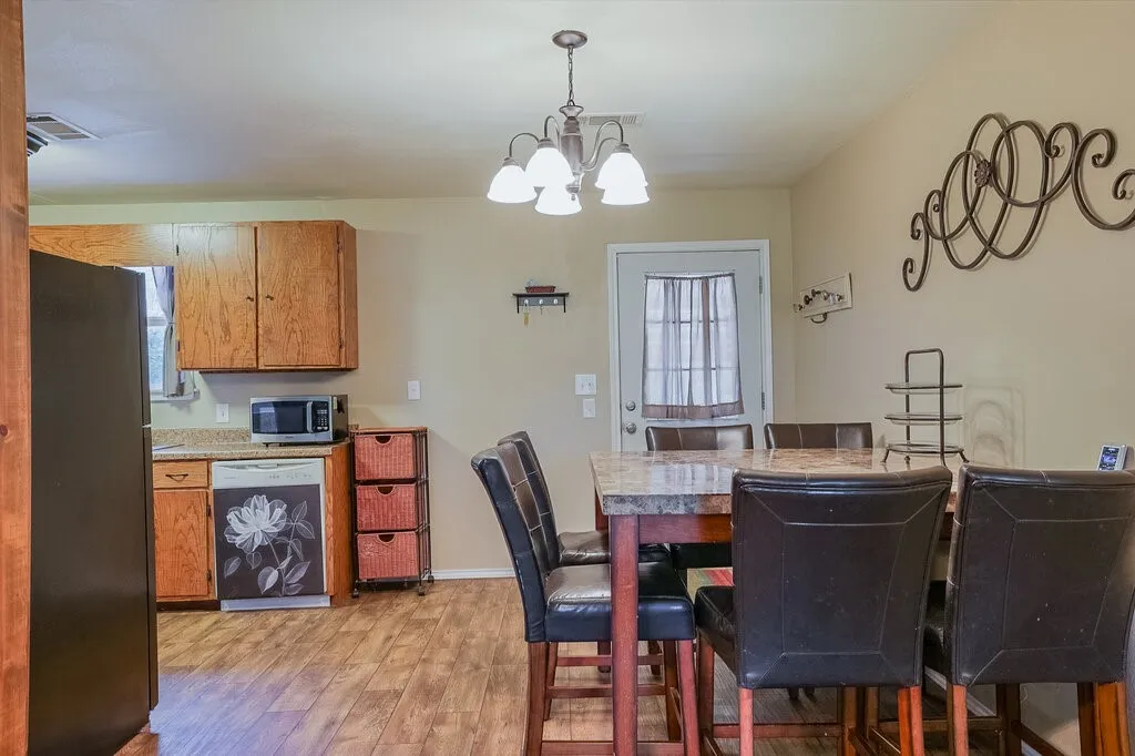 Kitchen area featuring wood-finish cabinetry, solid-surface countertops, wood-finish flooring, and a multi-light chandelier