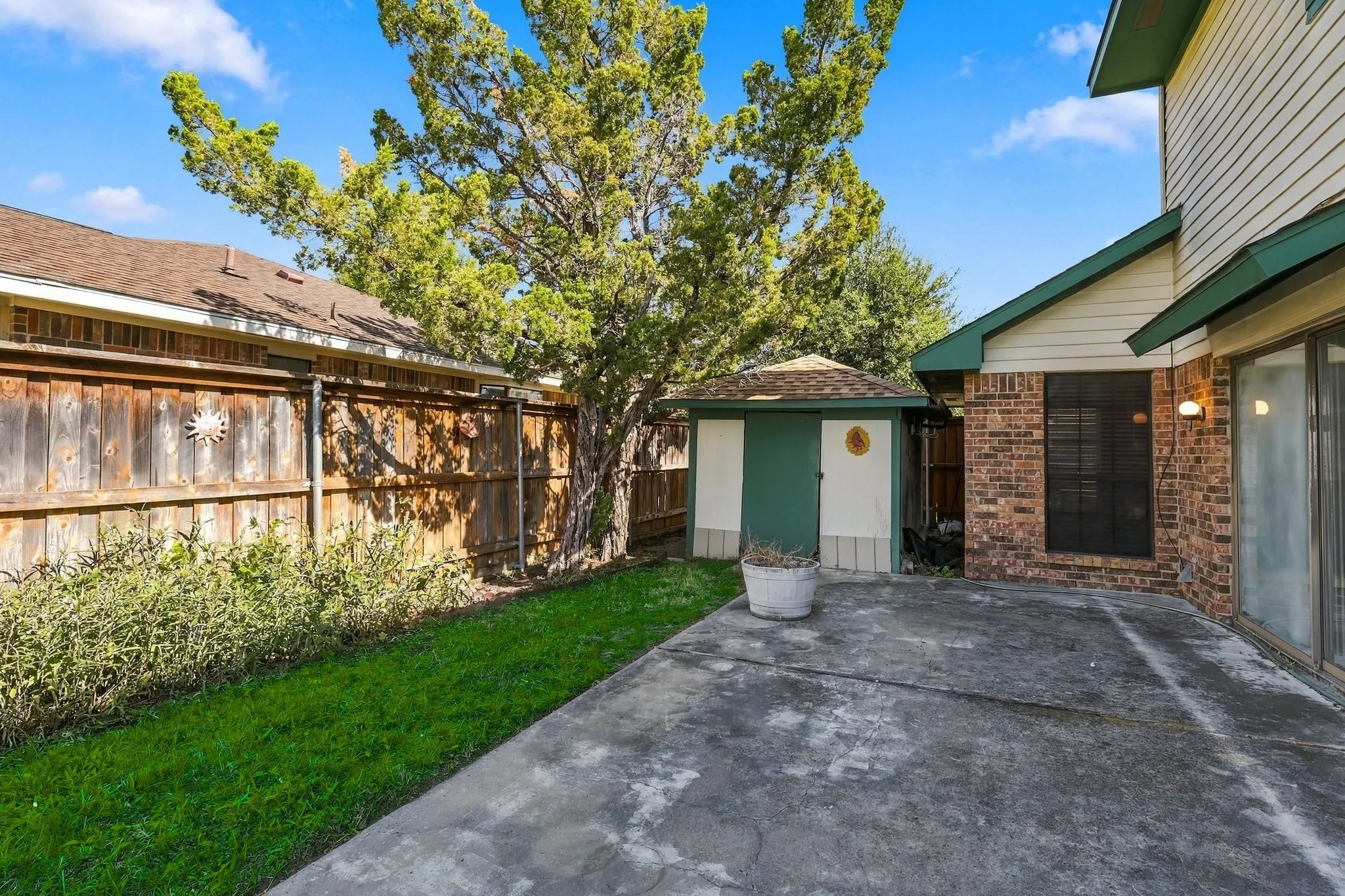 Additional side patio space with a storage shed in need of repair.