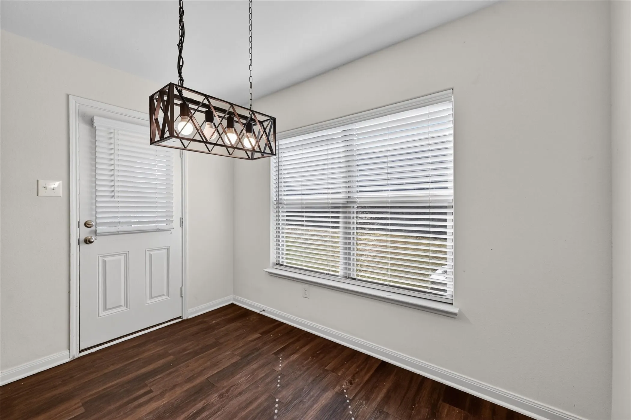 Rectangular four-light caged chandelier with a metal finish, wood-finish flooring, dual-pane window with integrated blinds, and glass-paneled exterior door