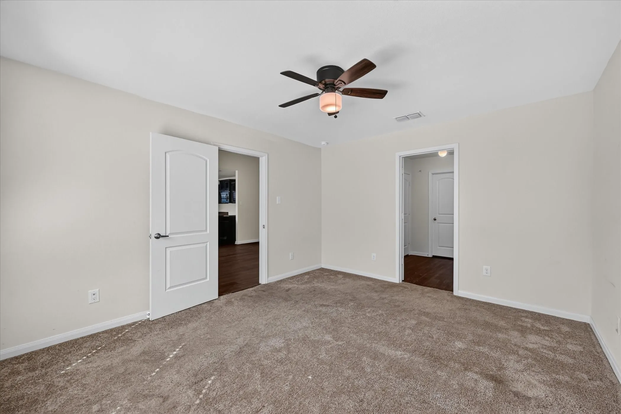 Interior space featuring neutral wall tones, plush wall-to-wall carpeting, a multi-blade ceiling fan with a centered light fixture, and arched-panel interior doors