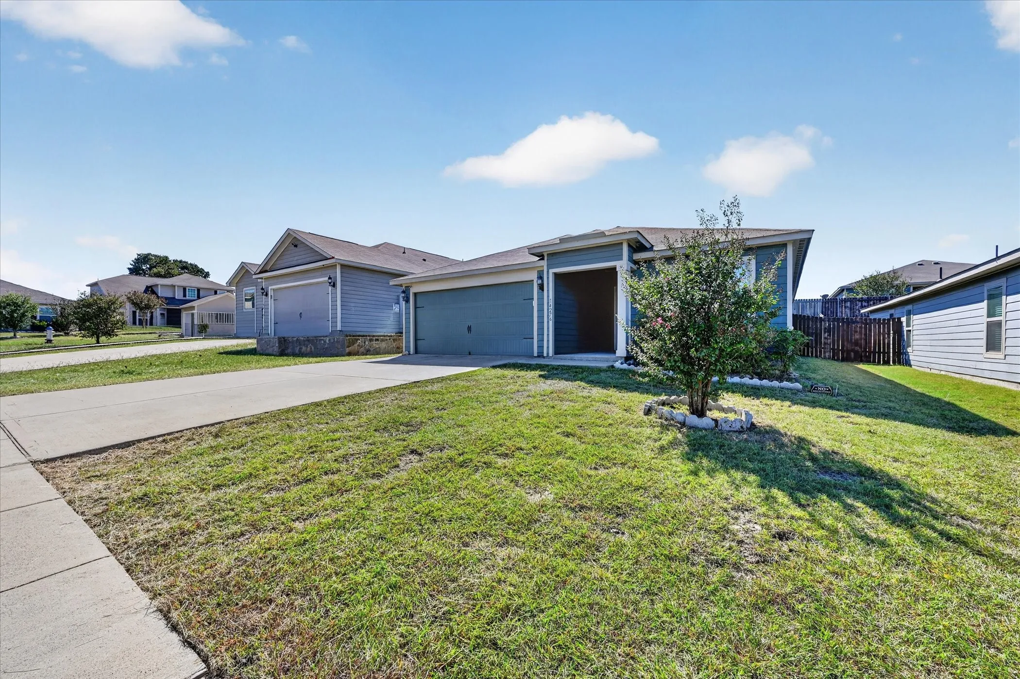 Single-story exterior featuring blue siding, a covered entryway, an attached two-car garage, and a concrete driveway