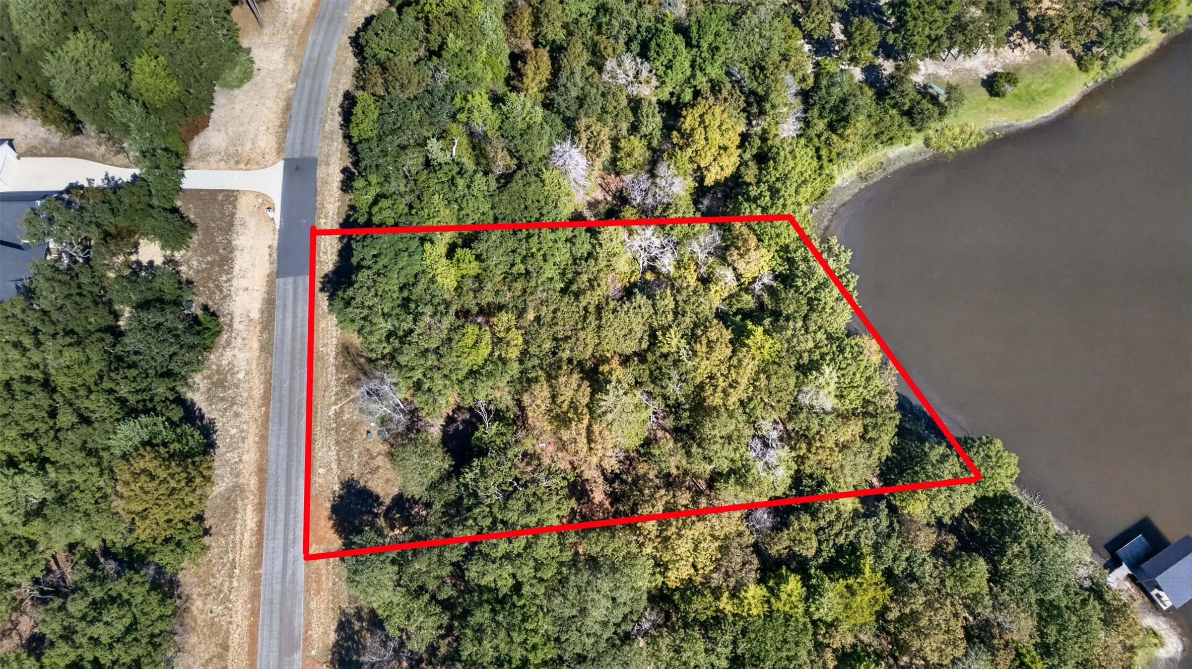 Wooded residential lot featuring extensive shoreline and direct paved road access