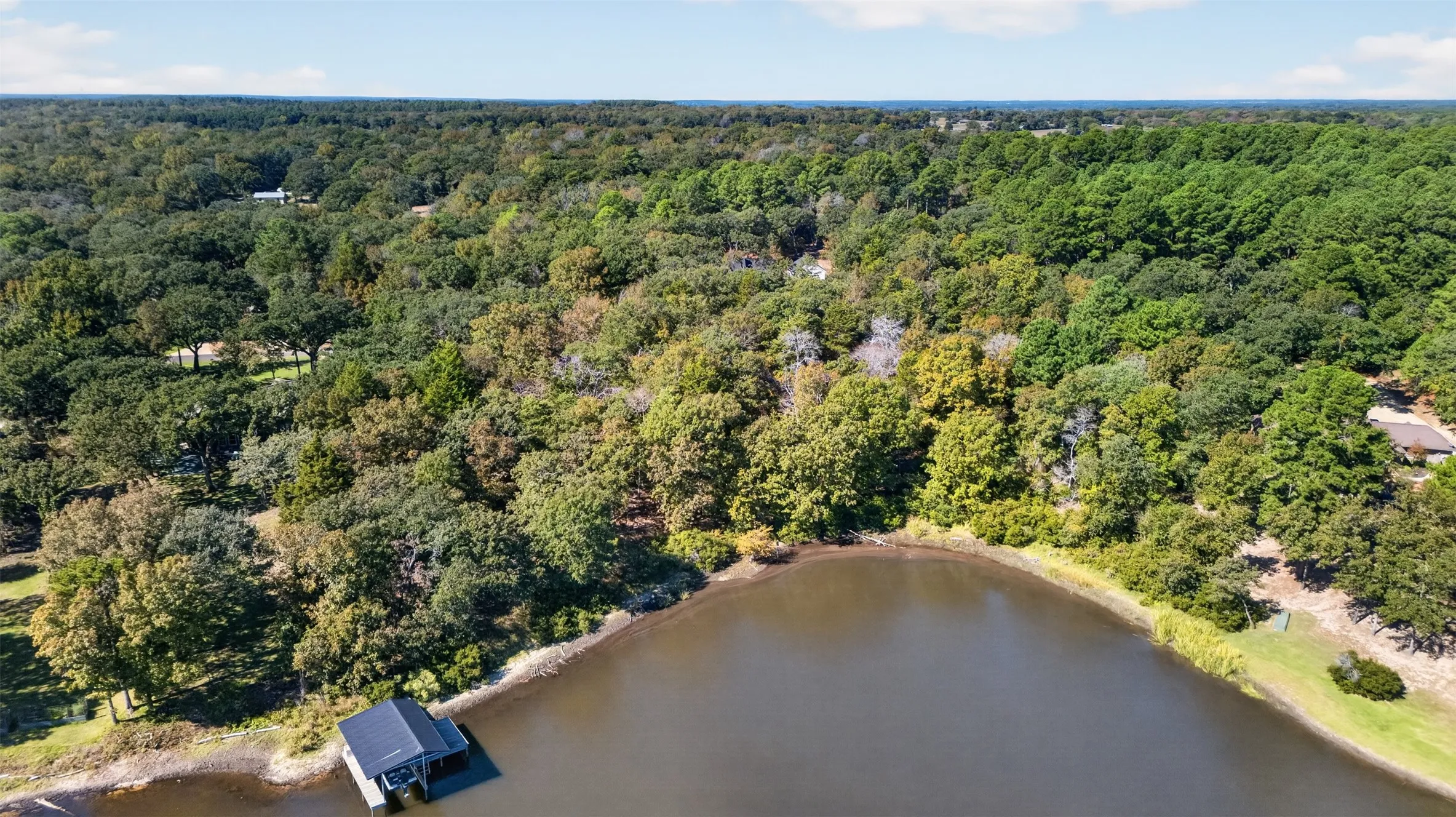 Waterfront property featuring a private boat dock, extensive shoreline, and mature hardwood tree coverage